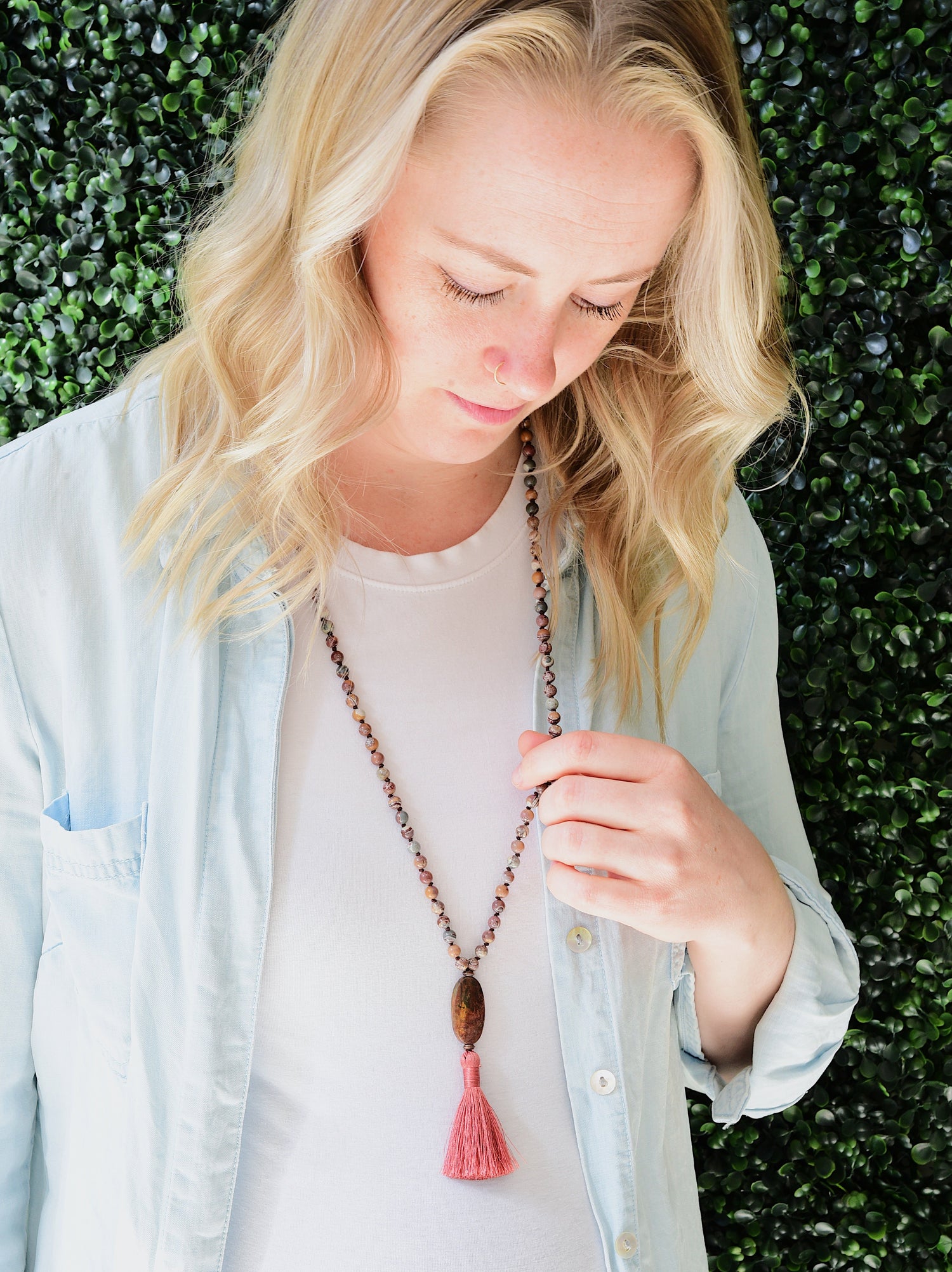 Grounded gemstone jewelry worn simply without spiritual labels. Woman wearing mala necklace.