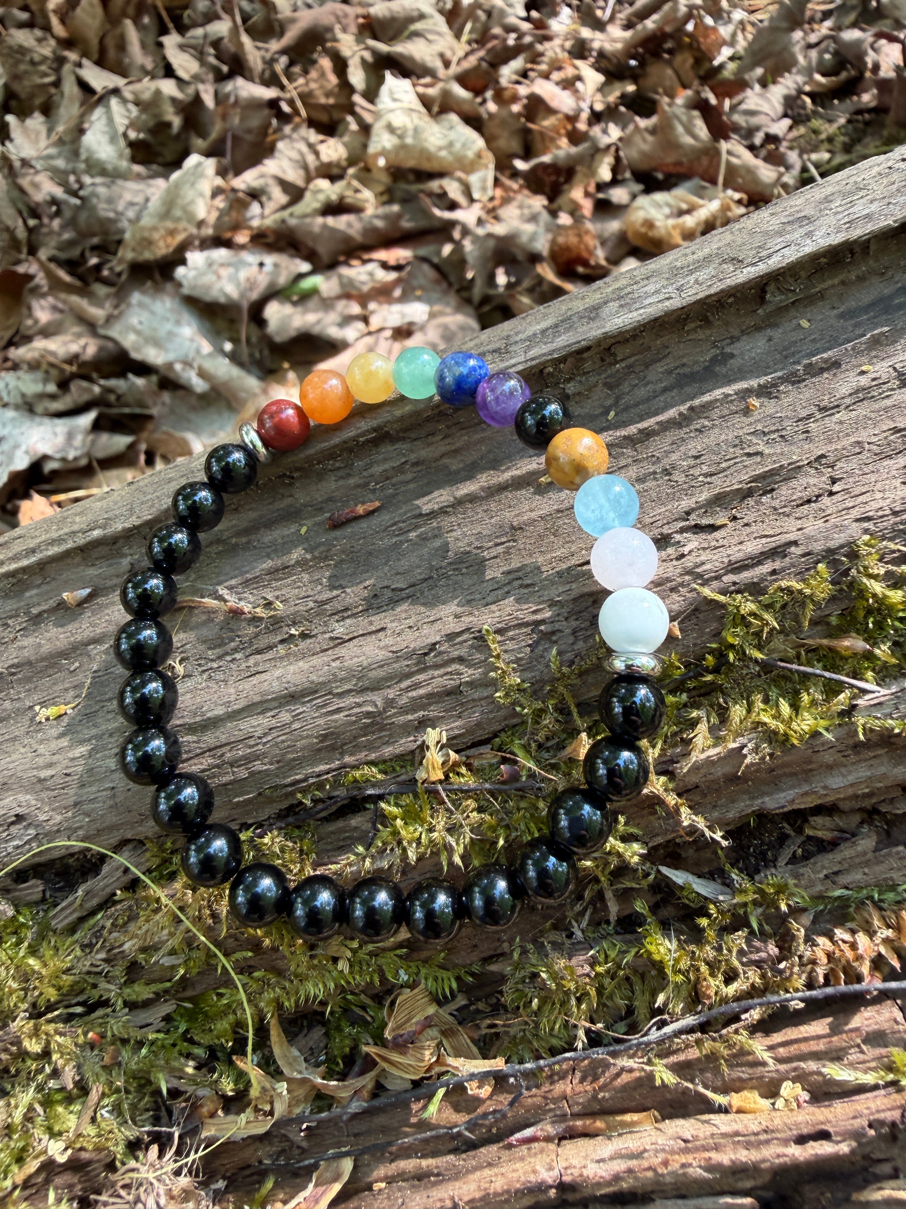 Multicolored beaded bracelet on a wooden surface with moss