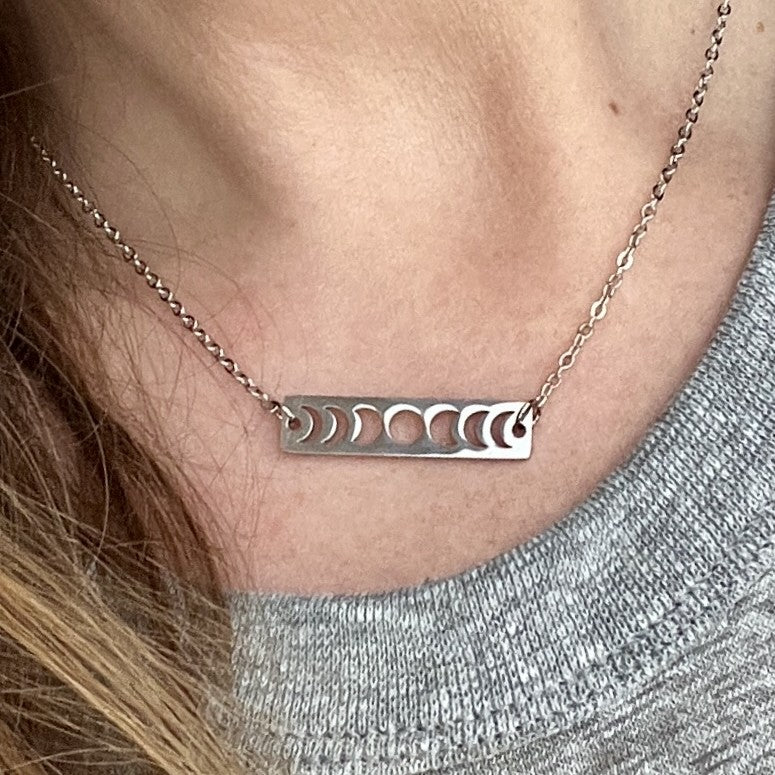 Silver necklace with moon phases worn by a person