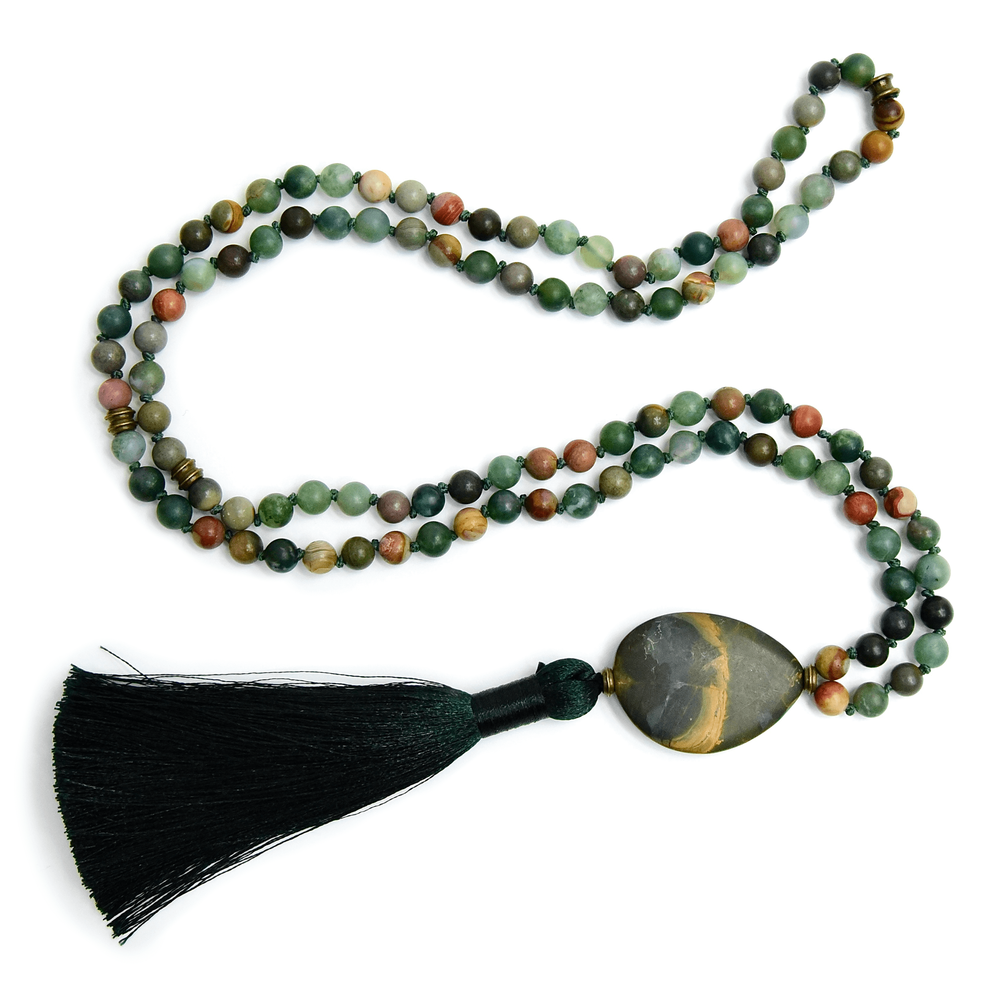 A mala necklace with a series of round beads in various shades of green and a red jasper bead, finished with a deep green tassel.