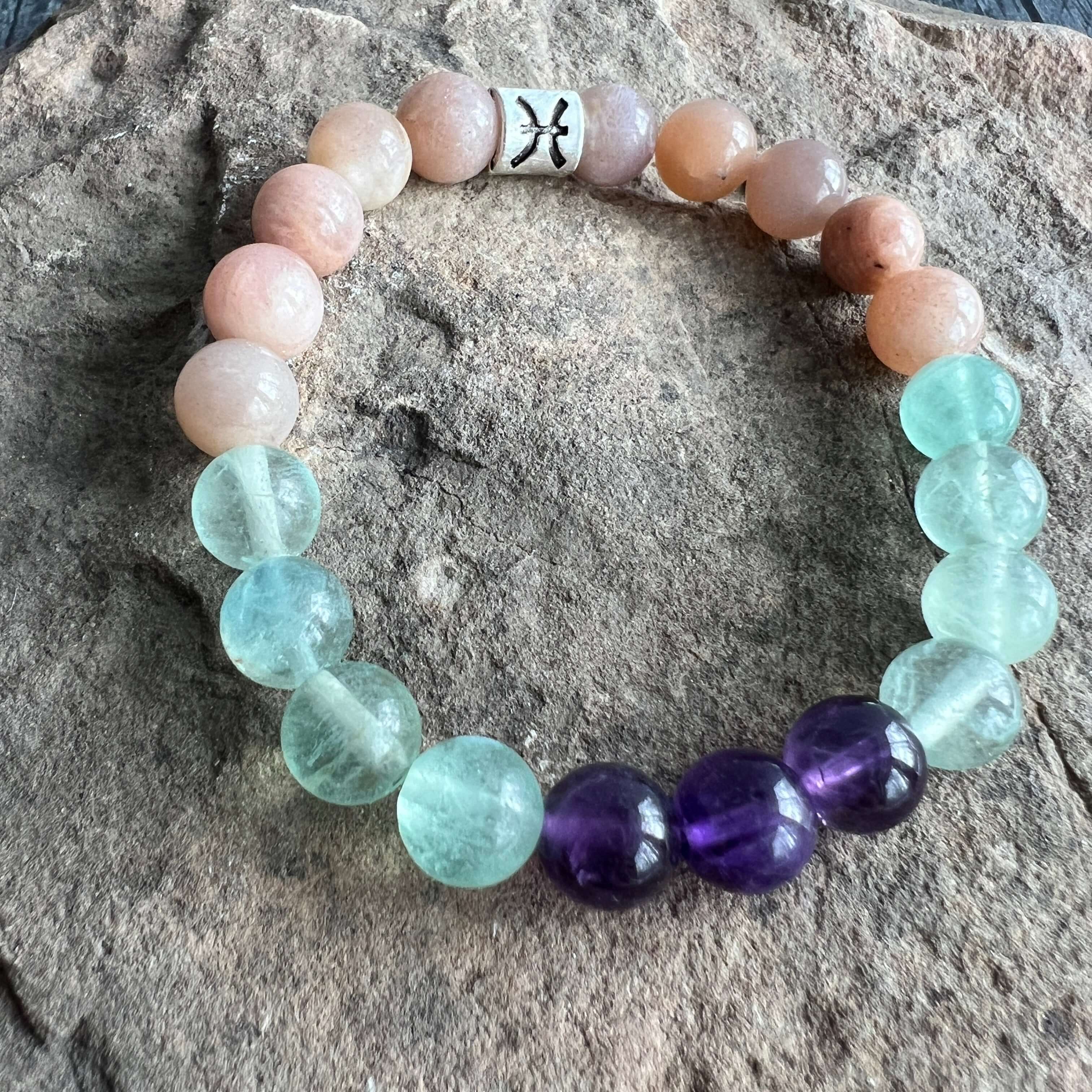 Pisces Zodiac Bracelet The Pisces Zodiac Bracelet is created with a combination of Amethyst, Green Fluorite, and Moonstone beads which resonate with the dreamy and intuitive qualities associated with this zodiac sign.