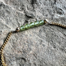 Load image into Gallery viewer, Close up of August birthstone bracelet made with 4mm faceted Peridot gemstones on gold plated chain.
