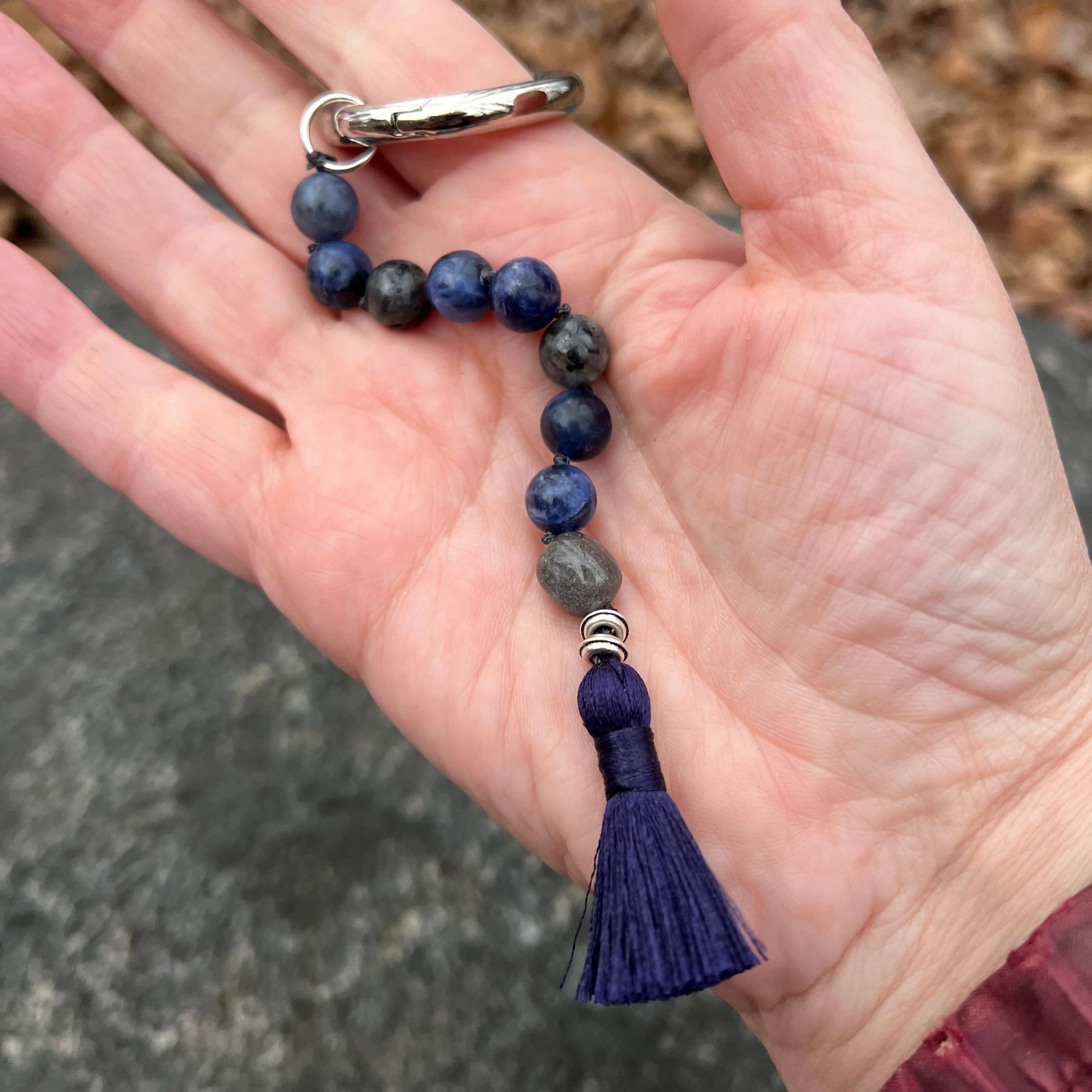 Beaded keychain with a tassel held in a hand against a blurred background