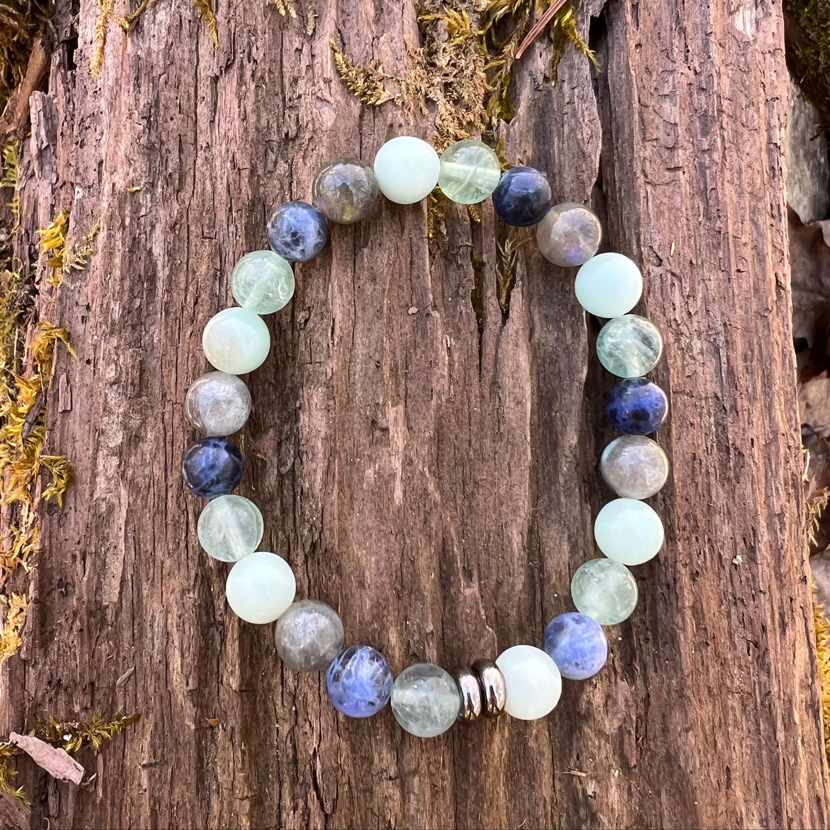 Amazonite, Fluorite, Labradorite, and Sodalite bead bracelet with stainless steel accent beads on a wood background.
