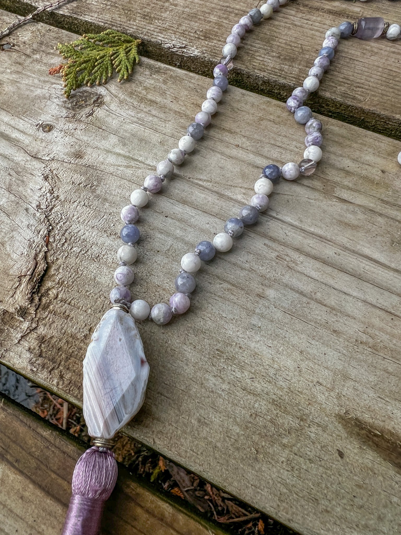 Morning Light 108 bead meditation mala with Botswana Agate focal stone and lavender tassel on weathered wood.