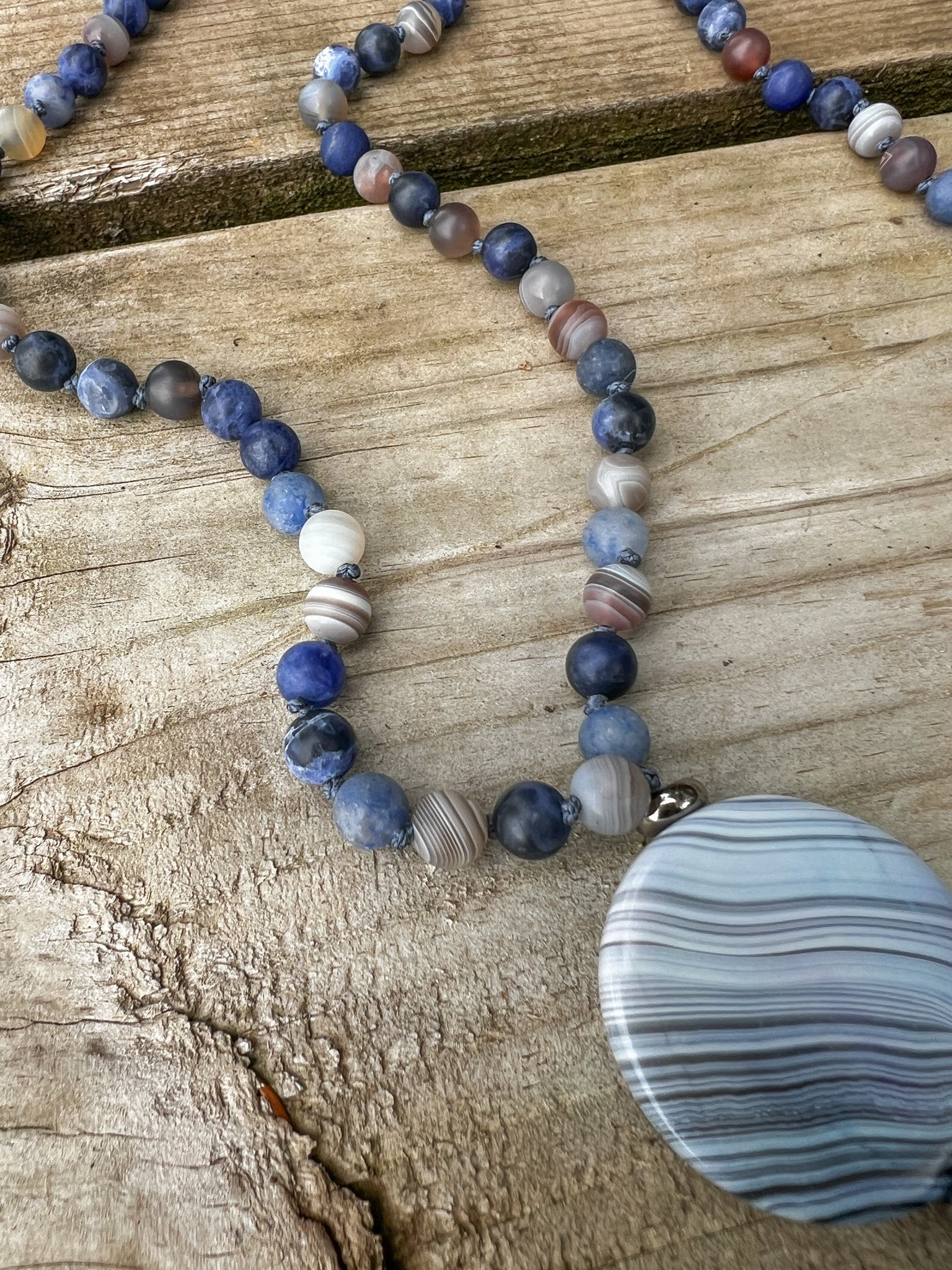 Detail of hand-knotted gemstones on the Ocean Current Mala Necklace showing natural patterns in Blue Aventurine, Sodalite, and Botswana Agate.