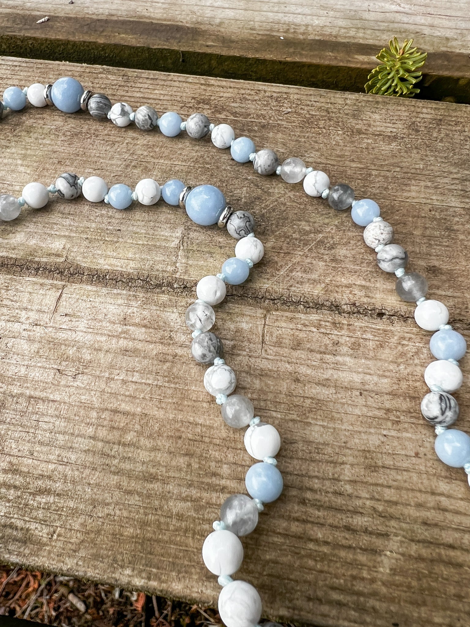 Detail of the Open Sky Mala Necklace showing the soft blue Angelite beads, Silver Crazy Lace Agate, and hand-knotted construction.