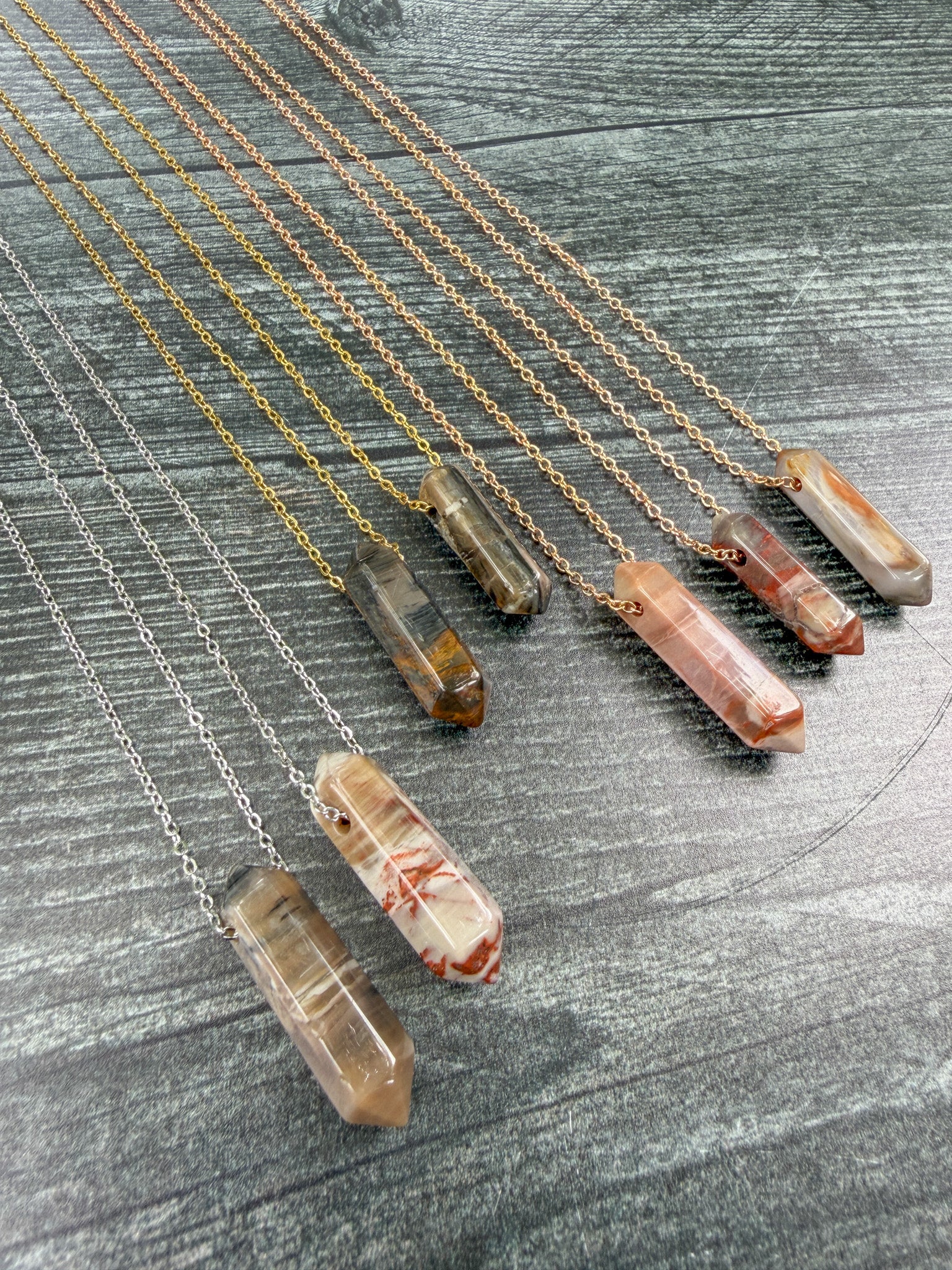 Earth Points Collection featuring seven unique Petrified Wood Agate Point Necklaces with gold, silver, and rose gold stainless steel chains at an angle.
