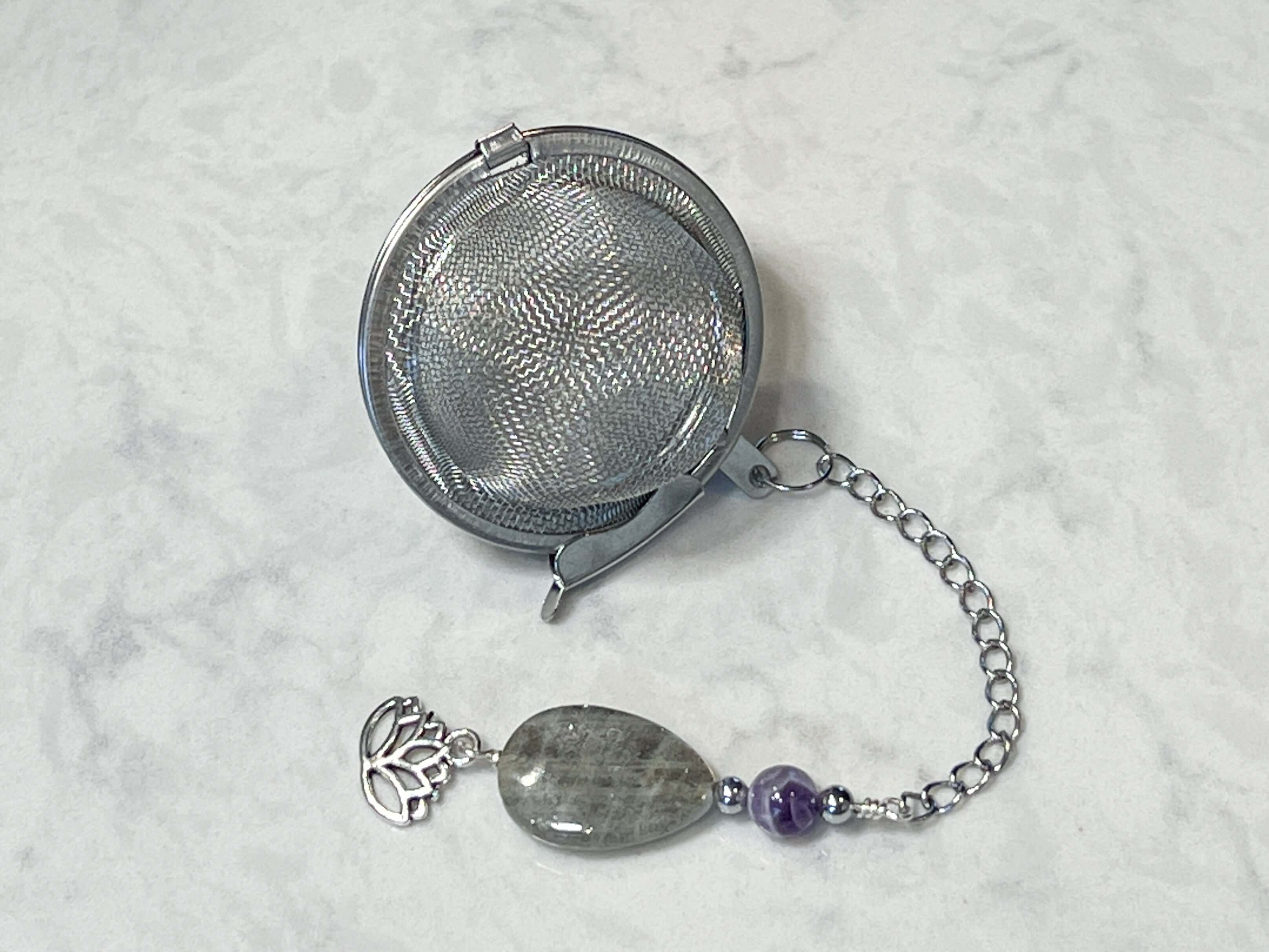 Amethyst and Labradorite Tea Strainer This tea strainer is made with a stainless steel tea ball, Chevron Amethyst, Labradorite, and Hematite beads. These stones offer clarity, transformation, and protection to the user.