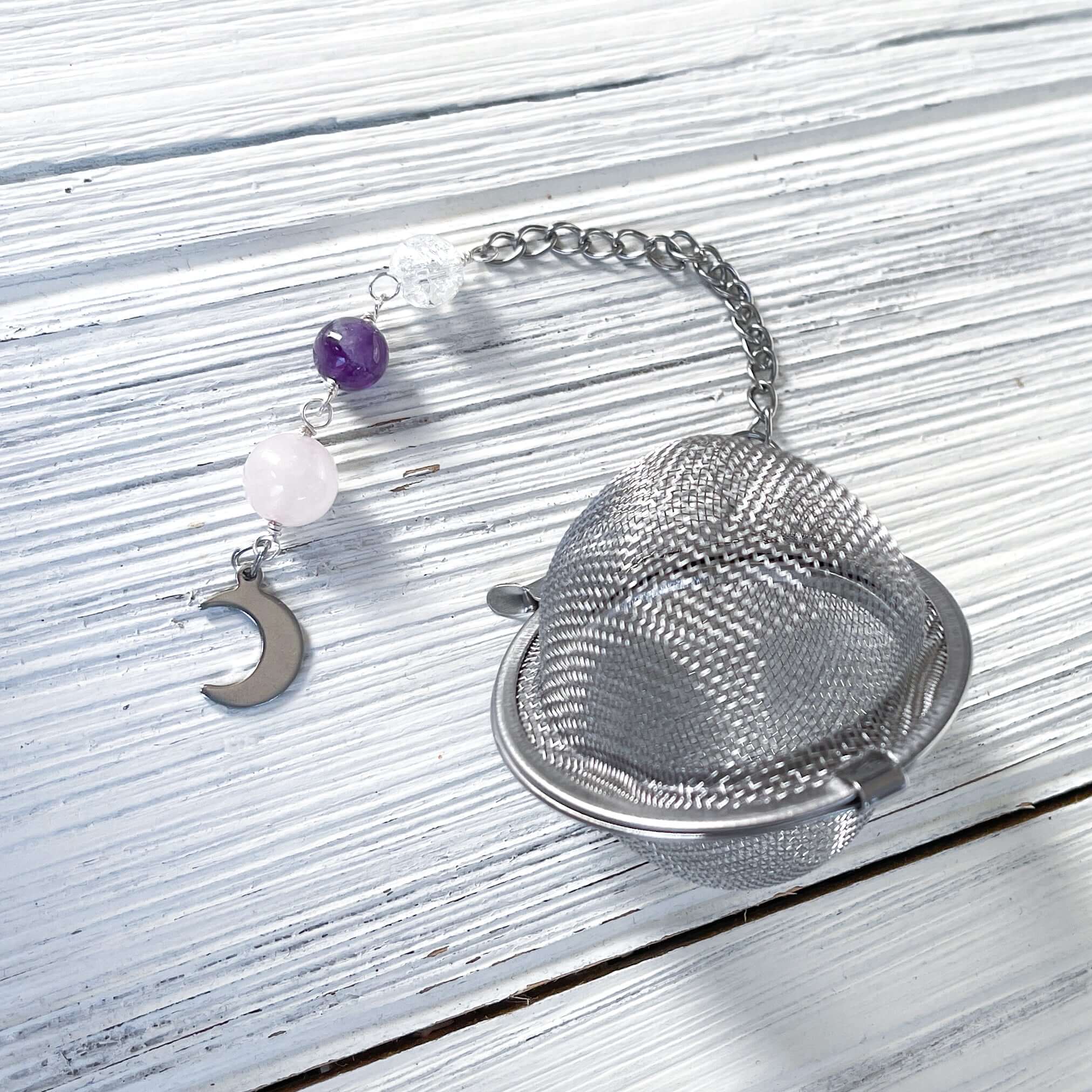 Amethyst and Quartz Tea Strainer This tea strainer is made with a stainless steel tea ball, Rose Quartz, Crystal Crackle Quartz, and Amethyst beads. These stones together bring the user mental clarity and universal love.