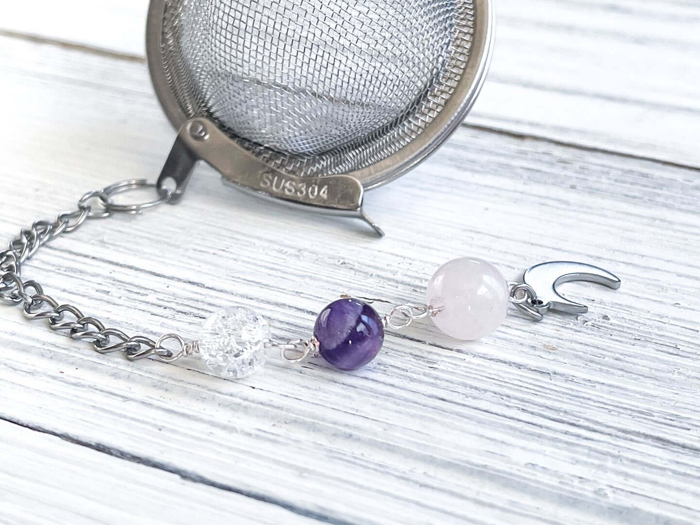 Amethyst and Quartz Tea Strainer This tea strainer is made with a stainless steel tea ball, Rose Quartz, Crystal Crackle Quartz, and Amethyst beads. These stones together bring the user mental clarity and universal love.