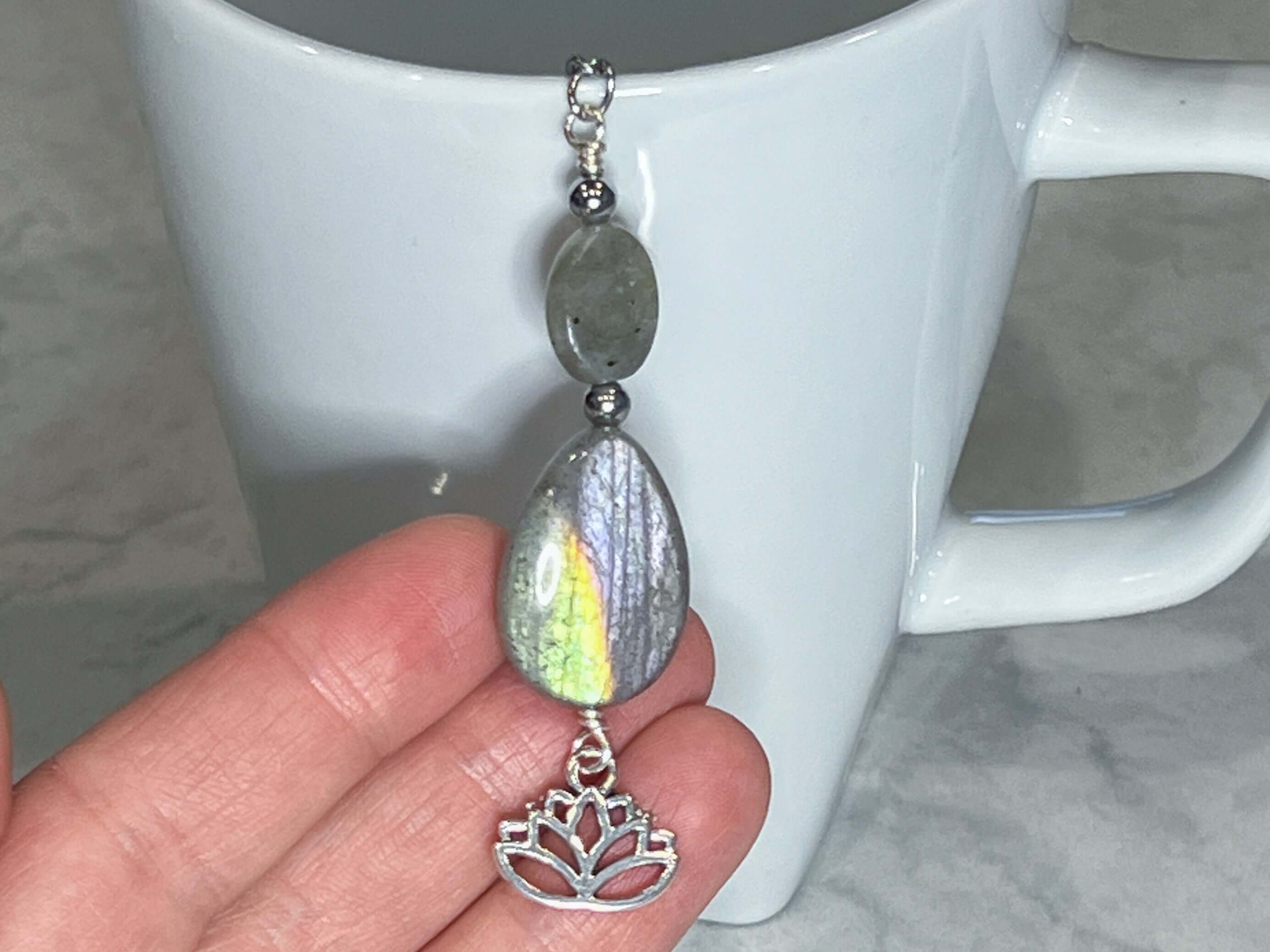 Labradorite Tea Strainer This tea strainer is made with a stainless steel tea ball, Labradorite and Hematite stones with a lotus flower charm. These stones bring the user protection and encourages spiritual transformation.