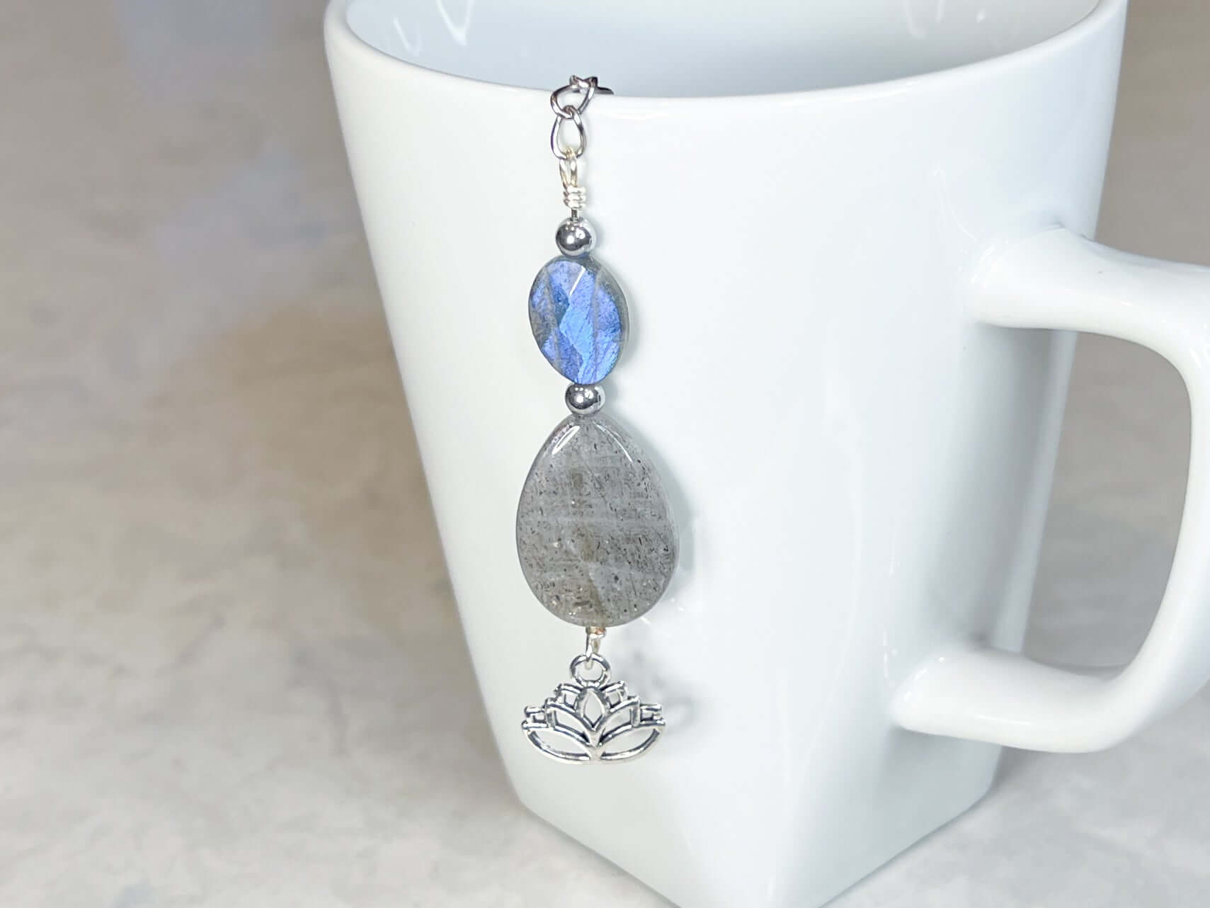 Labradorite Tea Strainer This tea strainer is made with a stainless steel tea ball, Labradorite and Hematite stones with a lotus flower charm. These stones bring the user protection and encourages spiritual transformation.