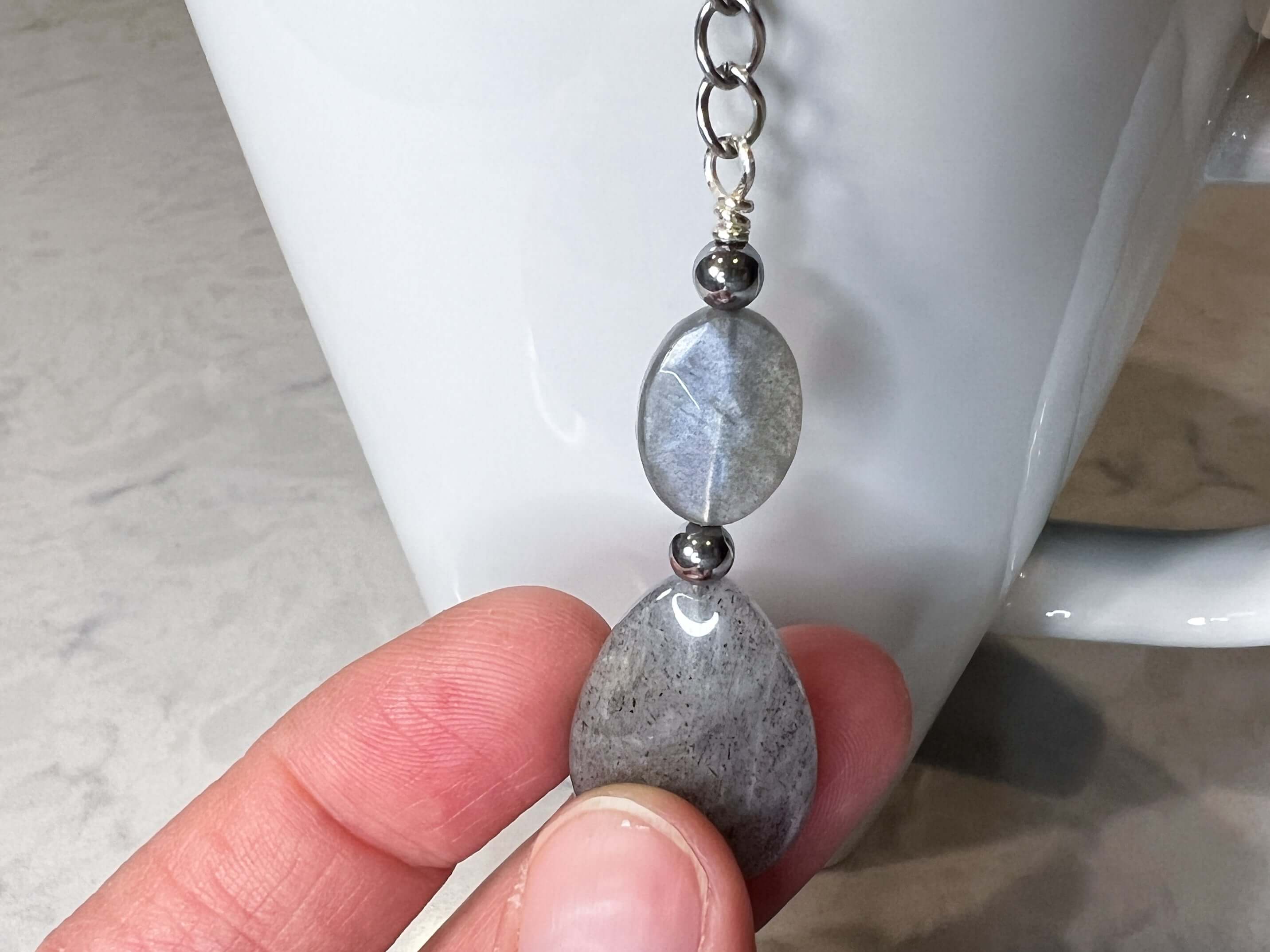 Labradorite Tea Strainer This tea strainer is made with a stainless steel tea ball, Labradorite and Hematite stones with a lotus flower charm. These stones bring the user protection and encourages spiritual transformation.