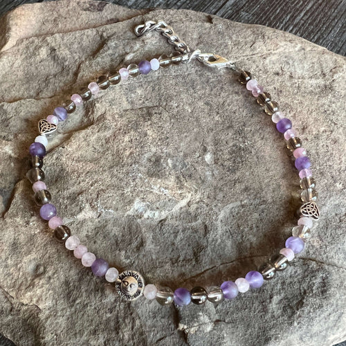 Cloudy Morning Beaded Anklet This anklet is made with high-quality Smoky Quartz, Rose Quartz, and Amethyst stones which bring love, peace, and serenity to the wearer. Zodiac Signs: Scorpio, Sagittarius, Capricorn, & Taurus. Chakras: Root, Solar Plexus, He