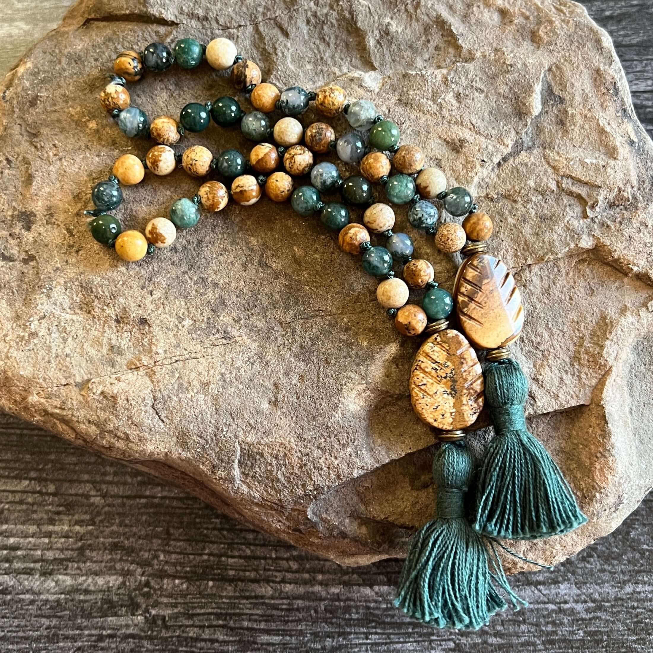 Pine Tree Quarter Mala This quarter mala is made with high-quality Picture Jasper and Moss Agate gemstones which bring confidence and abundance to the wearer. Zodiac Signs: Leo, Capricorn, & Virgo. Chakras: Root, Third Eye, & Heart. Handmade with authenti