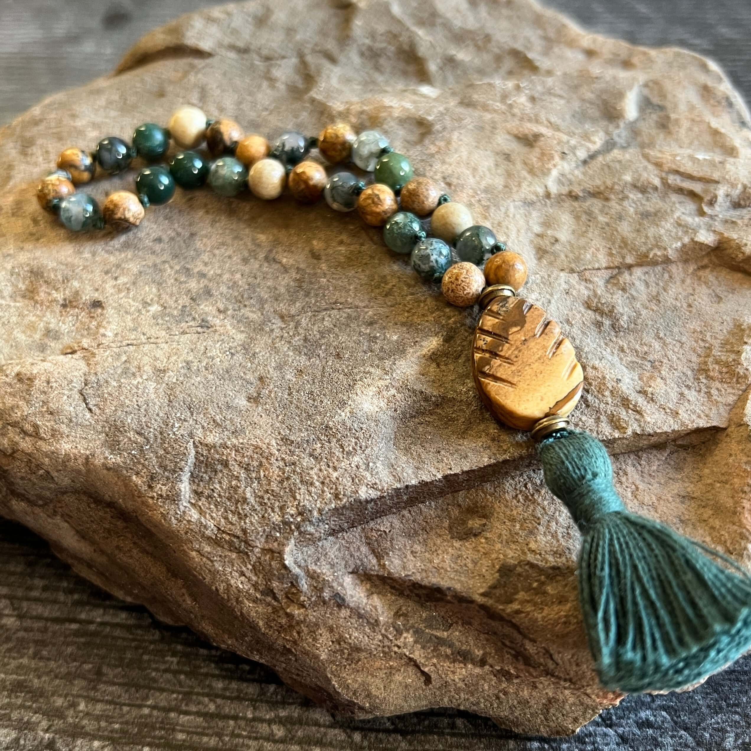 Pine Tree Quarter Mala This quarter mala is made with high-quality Picture Jasper and Moss Agate gemstones which bring confidence and abundance to the wearer. Zodiac Signs: Leo, Capricorn, & Virgo. Chakras: Root, Third Eye, & Heart. Handmade with authenti