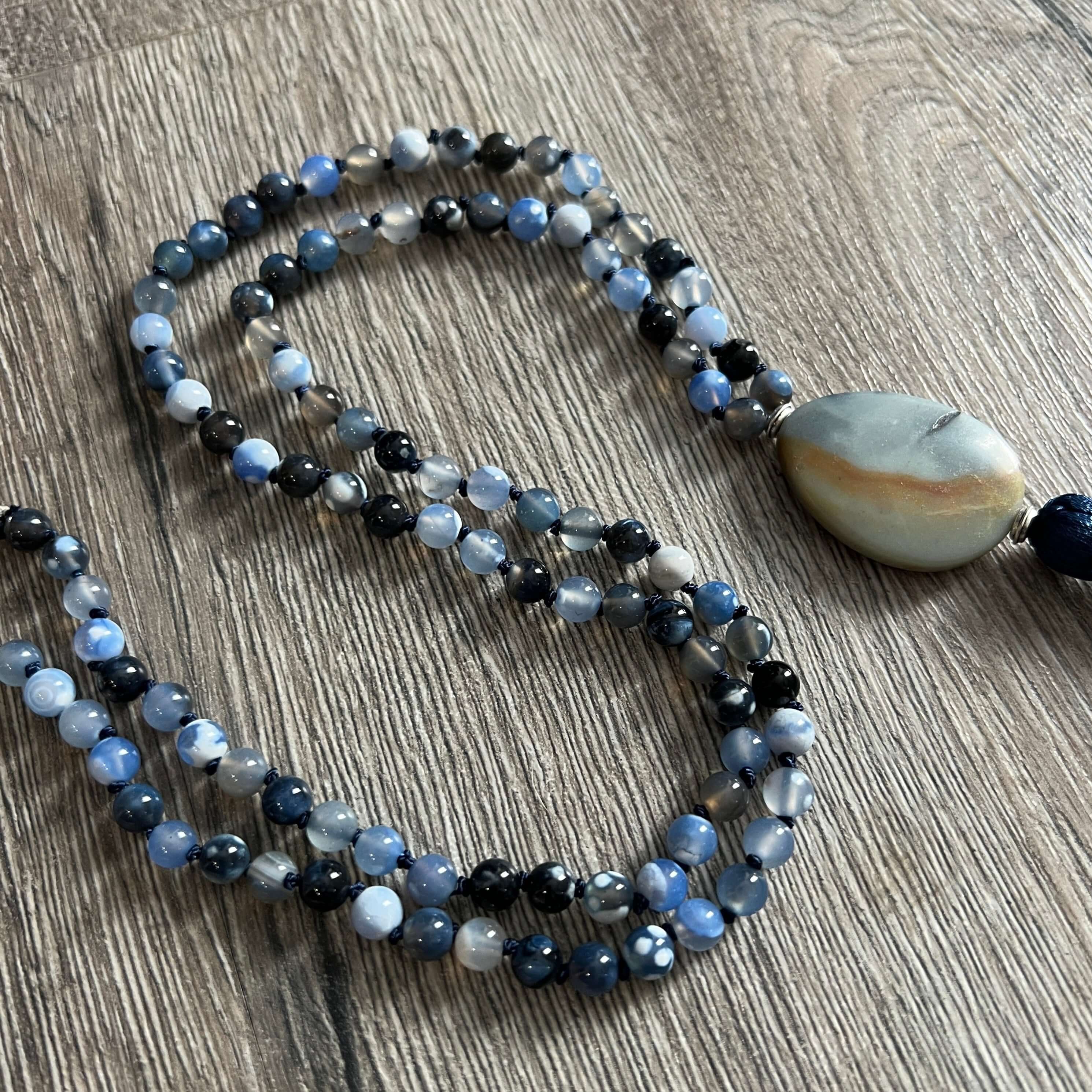 Winter Morning Mala This mala was made with Black-Blue Agate and Amazonite gemstones which provide strength and inspiration to the wearer. Zodiac Signs: Gemini & Virgo. Chakras: Third Eye, Root, Crown, Throat & Heart. Handmade with authentic crystals and