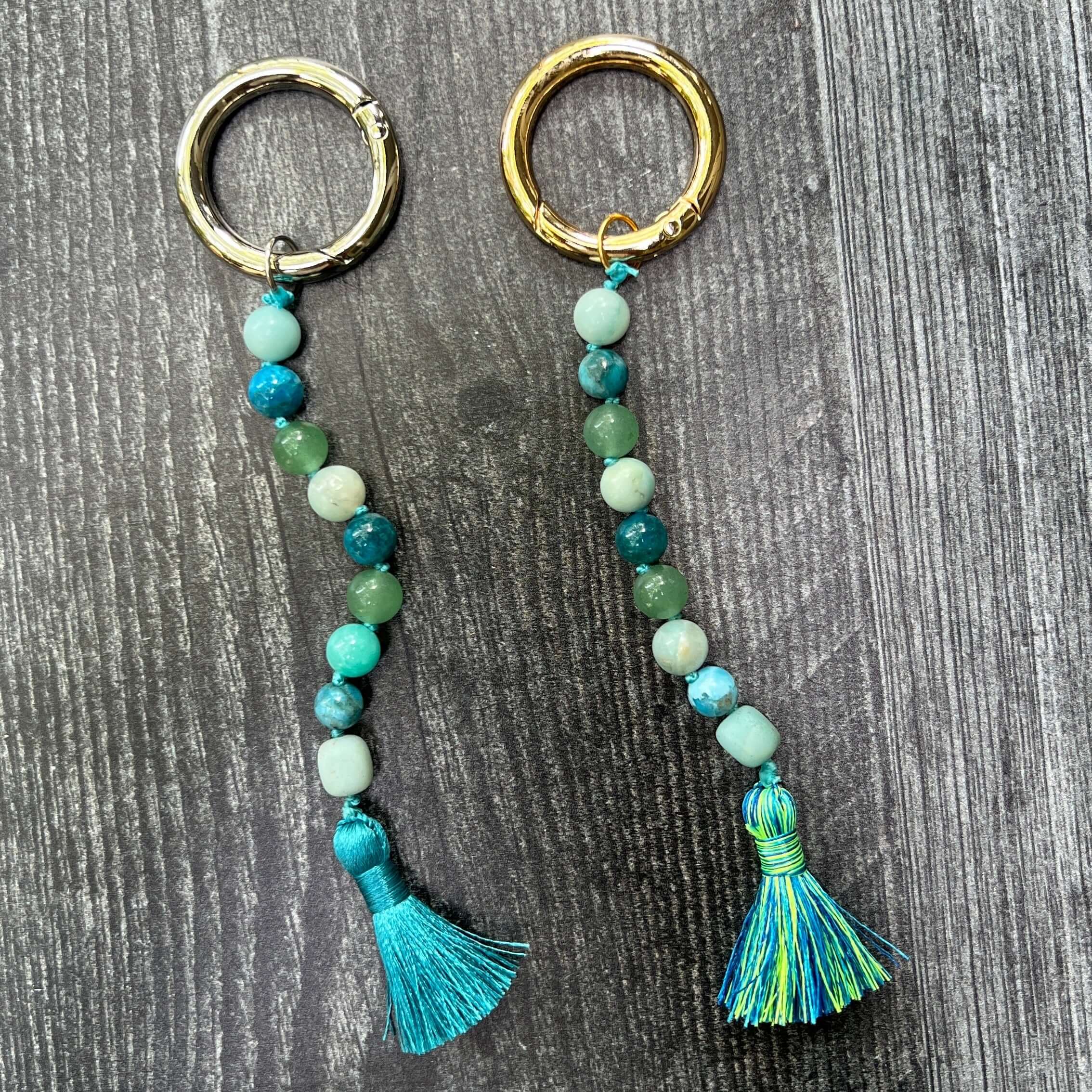 Two beaded keychains with tassels on a wooden surface