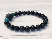 Load image into Gallery viewer, Lava Stone Focal Bracelet with African Turquoise This bracelet is made with a Lava stone focal bead, African Turquoise, and Rainbow Obsidian. These stones together bring light to the most blocked and stagnant energy and give the wearer strength to pursue
