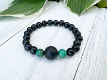 Load image into Gallery viewer, Lava Stone Focal Bracelet with African Turquoise This bracelet is made with a Lava stone focal bead, African Turquoise, and Rainbow Obsidian. These stones together bring light to the most blocked and stagnant energy and give the wearer strength to pursue
