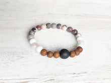 Load image into Gallery viewer, Lava Stone Focal Bracelet with Sandalwood This bracelet is made with a Lava focal bead, Sandalwood, White Jade, pink Morganite, and Porcelain Jasper. Together these stones work together to bring the wearer a sense of tranquility, love, and abundance.
