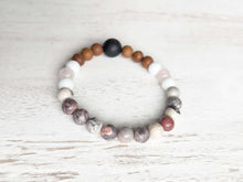 Load image into Gallery viewer, Lava Stone Focal Bracelet with Sandalwood This bracelet is made with a Lava focal bead, Sandalwood, White Jade, pink Morganite, and Porcelain Jasper. Together these stones work together to bring the wearer a sense of tranquility, love, and abundance.
