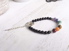 Load image into Gallery viewer, Obsidian Chakra Bracelet This bracelet is made with black obsidian, and chakra stones with a lotus charm. These stones together help the wearer balance the energy of their chakras. Stones include Jasper, Aventurine, Moonstone, Turquoise, Sodalite, Amethys
