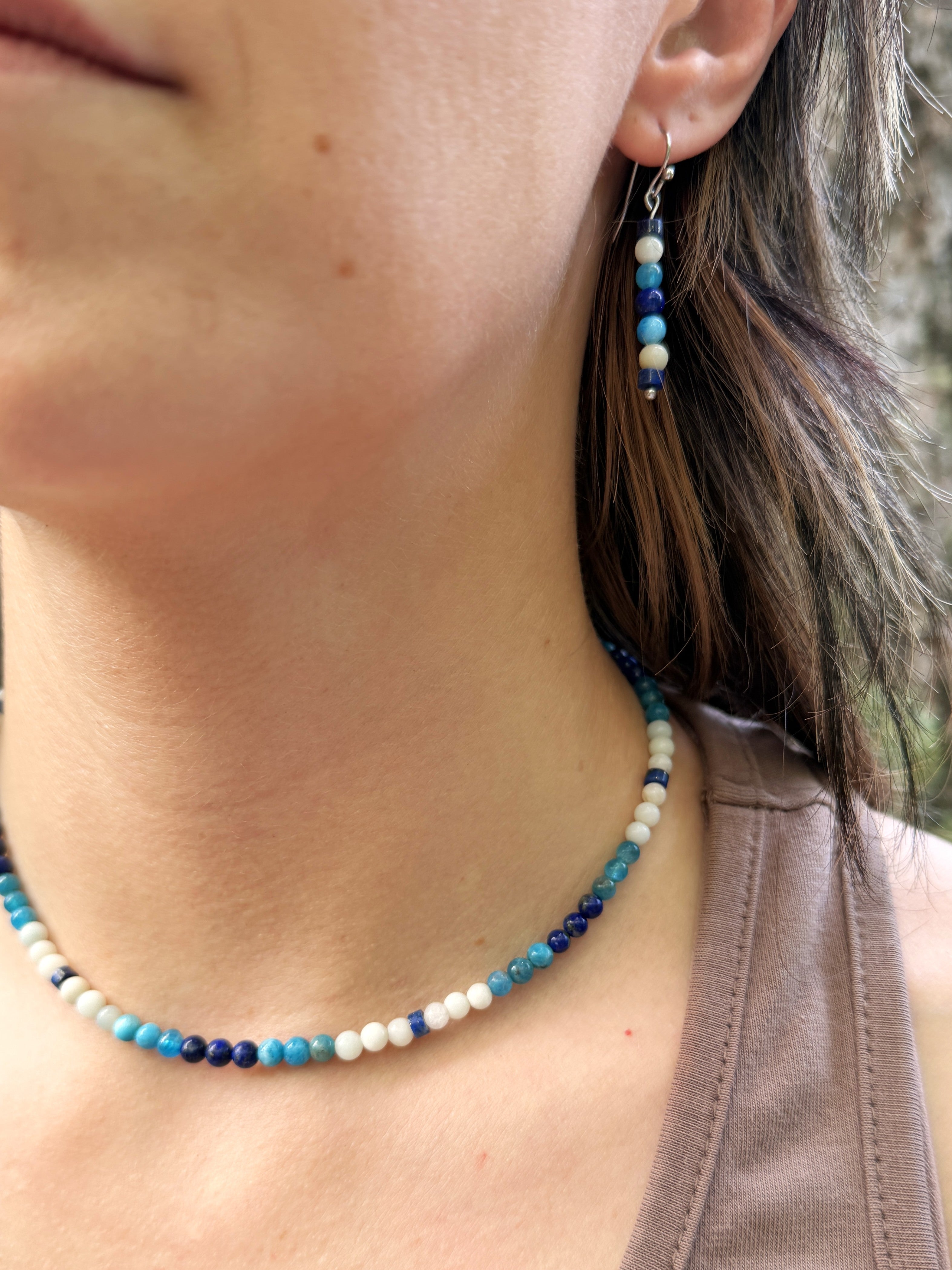Blue and white beaded necklace and earrings on model.