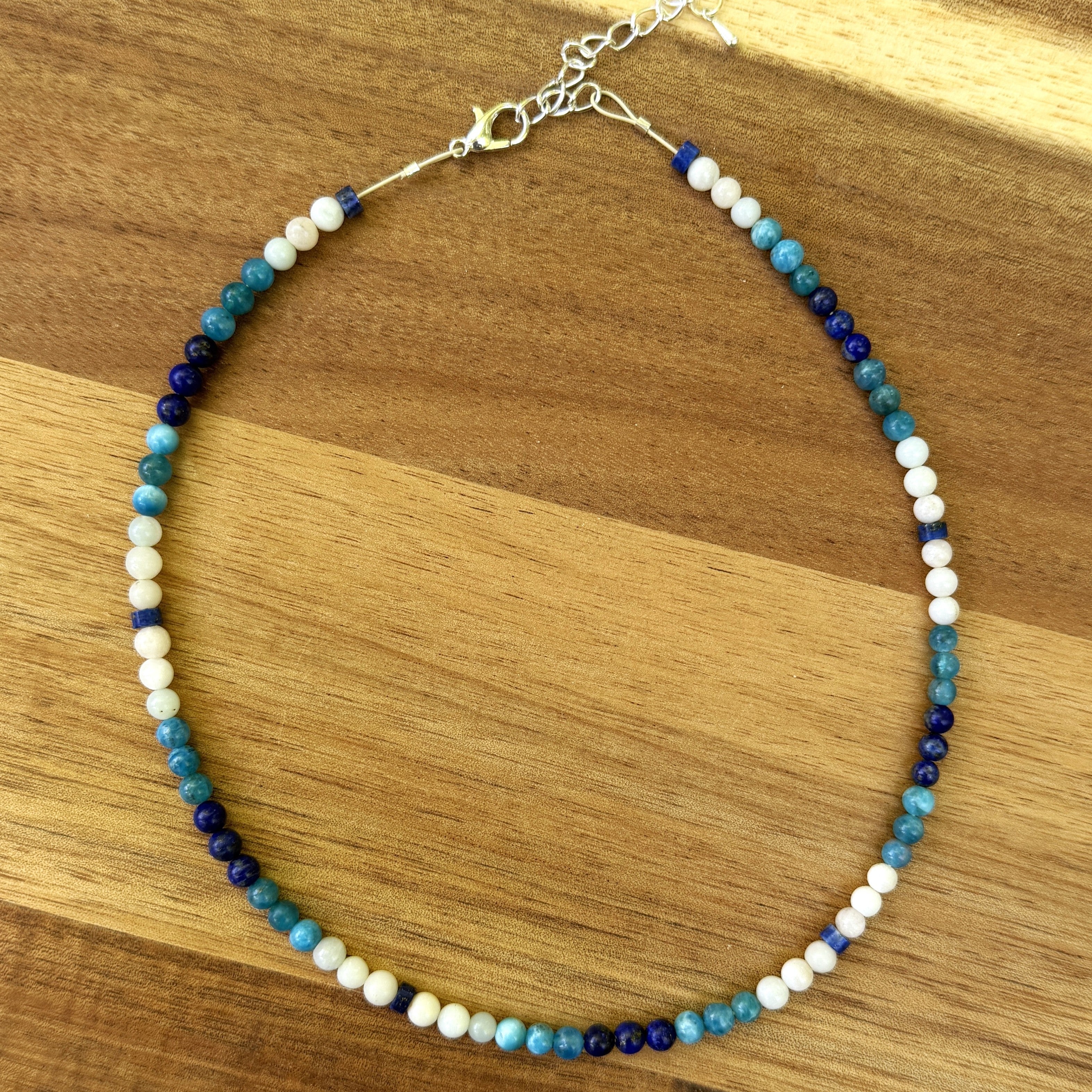 Blue and white beaded necklace on wood background.