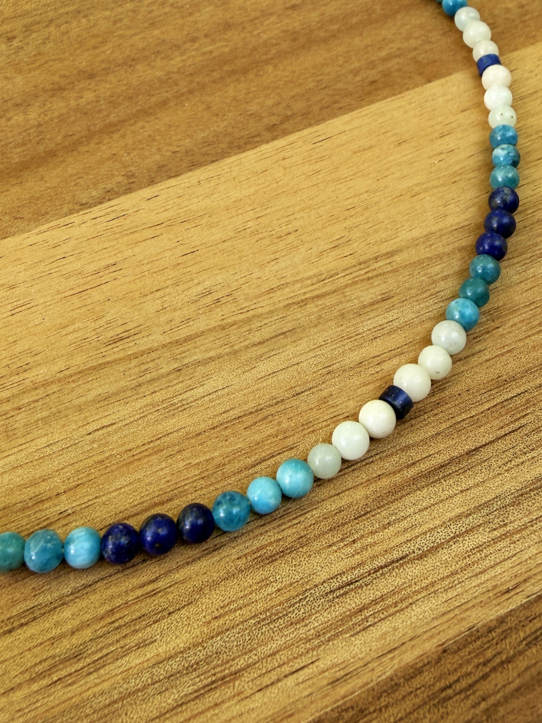 Close up of blue and white beaded necklace on wood background.
