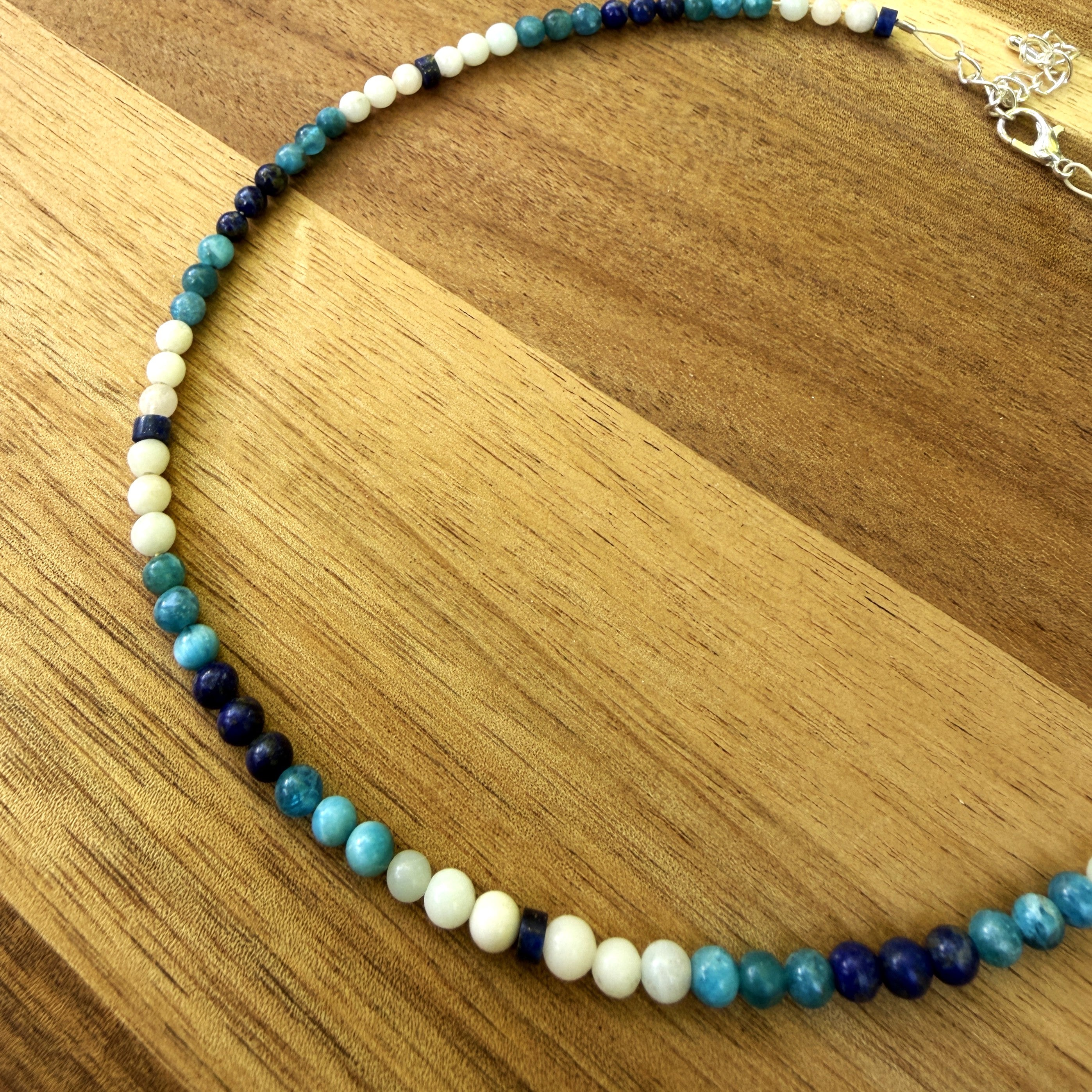 Close up of blue and white beaded necklace on wood background.