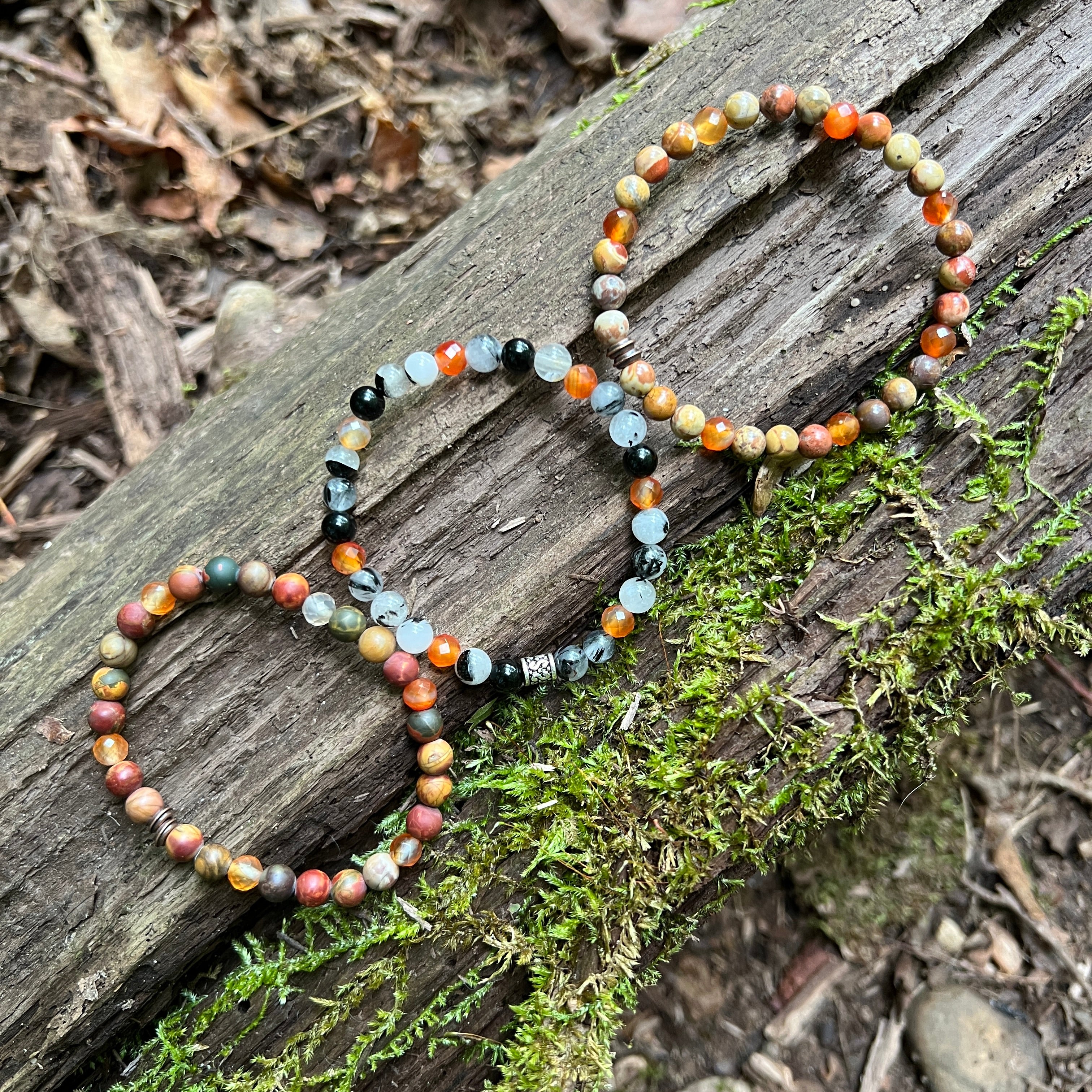3 beaded bracelets from Fall Collection with a log and moss background