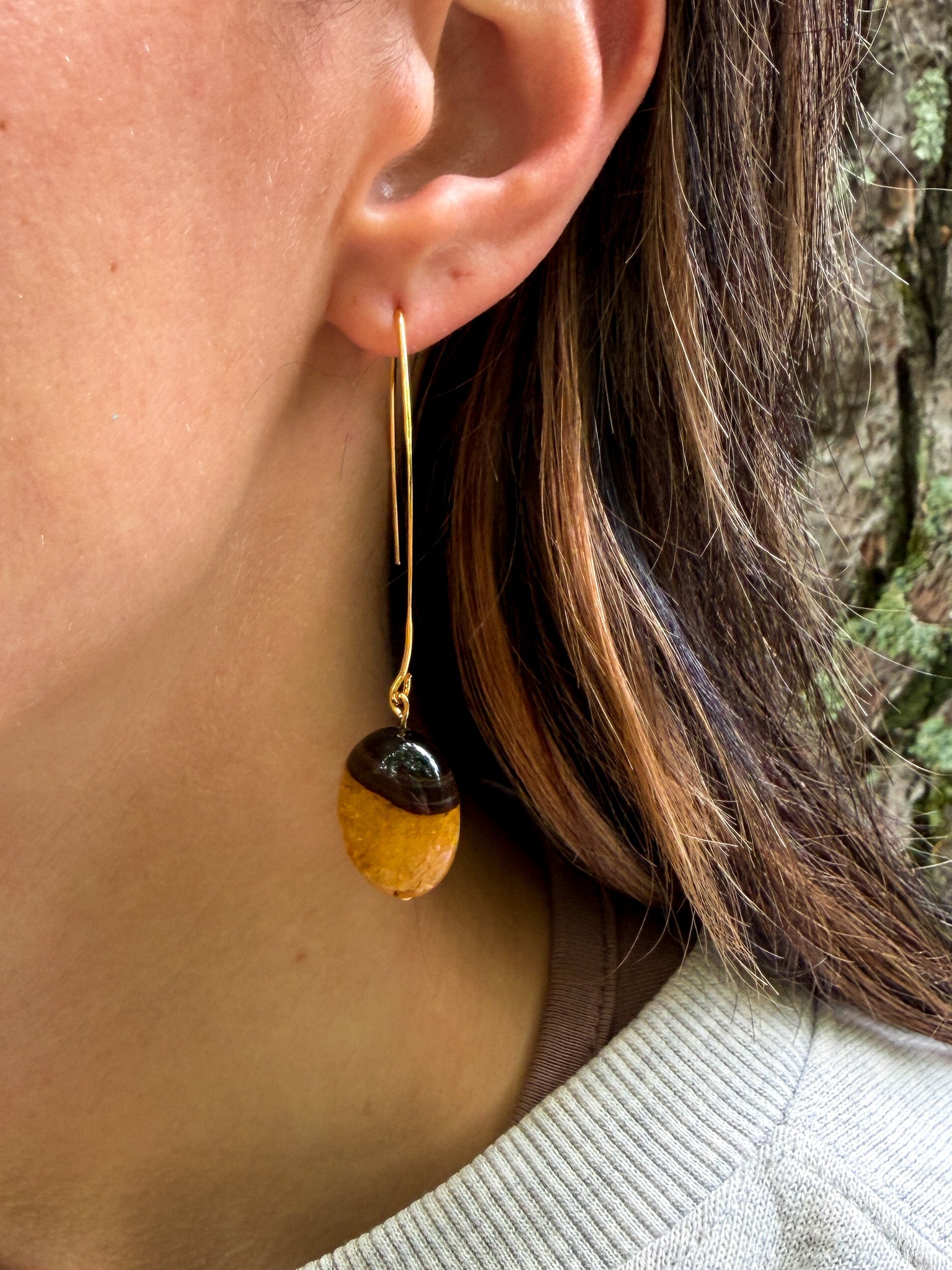 Natural Bumblebee Agate earrings with oval gemstones and gold-plated stainless steel elongated ear wires on model