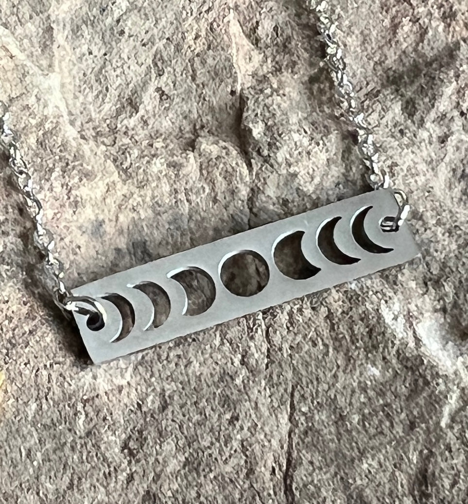 Silver necklace with moon phase design on a stone background