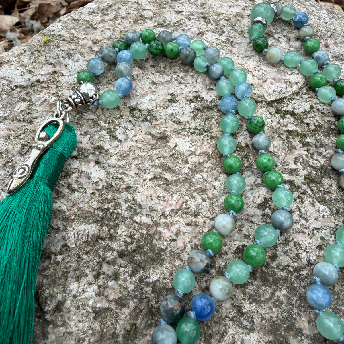Necklace with green tassel and multicolored beads on a stone surface
