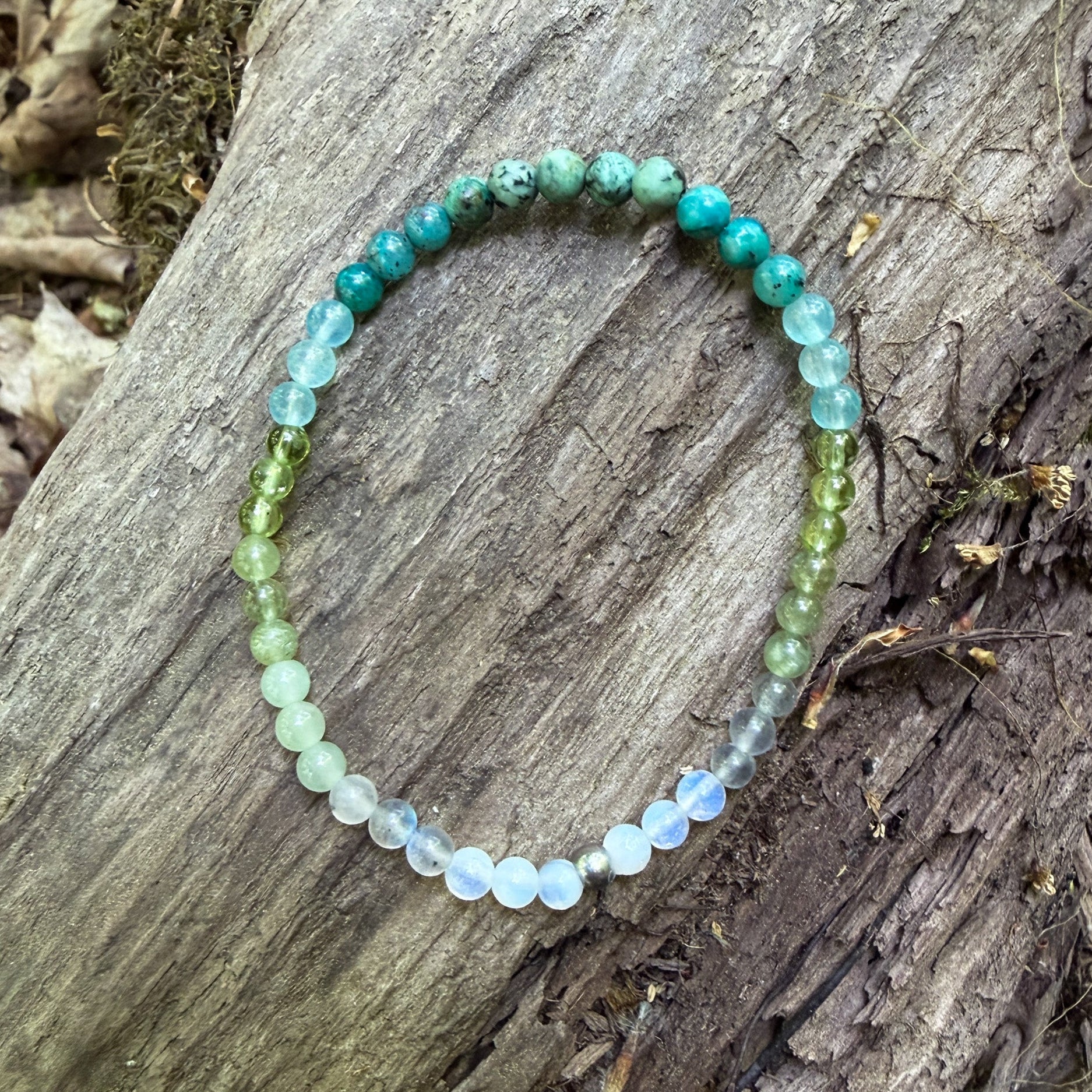 Beaded bracelet with green and blue stones on a wooden surface