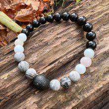 Load image into Gallery viewer, Lava Stone Focal Bracelet with Rainbow Obsidian This bracelet is made with a Lava stone focal bead, Gray Map Jasper, White Jade, Pink Morganite, and Rainbow Obsidian. Together these stones bring the wearer a sense of relaxation, and a release of stagnant
