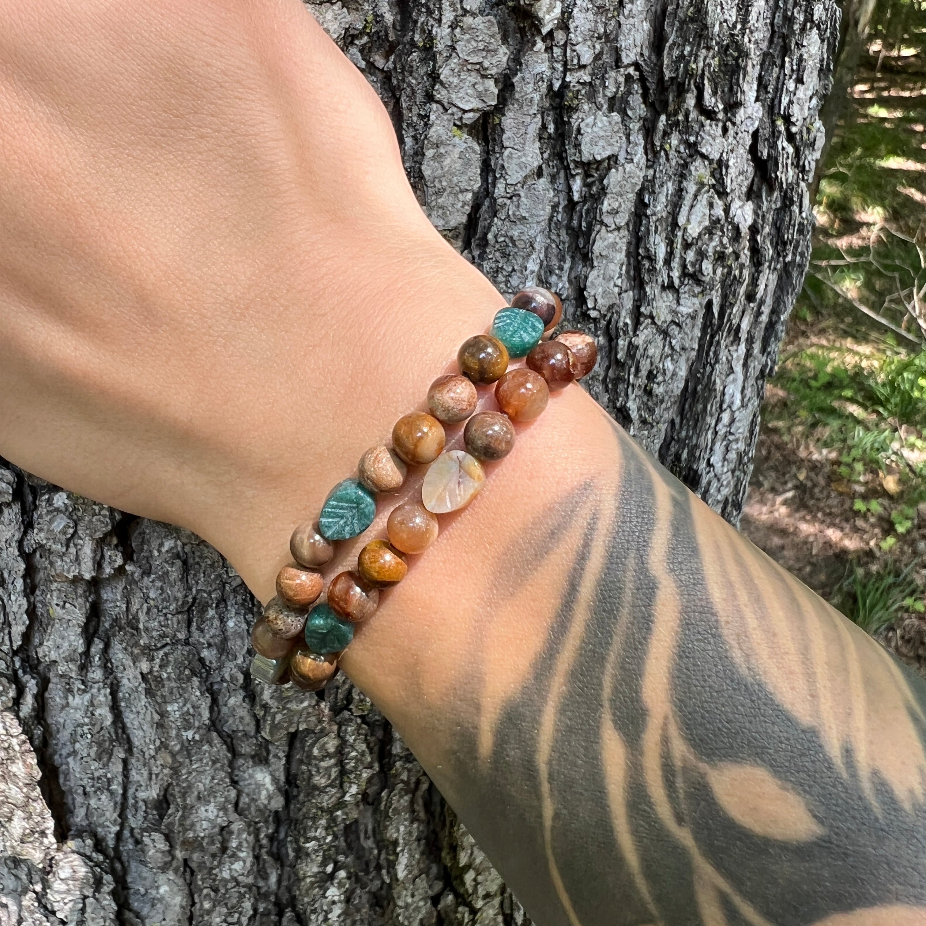 Bracelet with agate and wood opal beads on a wrist against a tree trunk background