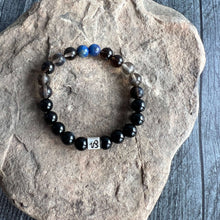 Load image into Gallery viewer, Capricorn Zodiac Bracelet The Capricorn Zodiac Bracelet is created with a combination of Lapis Lazuli, Smoky Quartz, and Onyx beads, which resonate with the strong and determined qualities associated with this zodiac sign.
