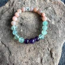 Load image into Gallery viewer, Pisces Zodiac Bracelet The Pisces Zodiac Bracelet is created with a combination of Amethyst, Green Fluorite, and Moonstone beads which resonate with the dreamy and intuitive qualities associated with this zodiac sign.
