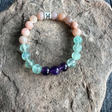 Pisces Zodiac Bracelet The Pisces Zodiac Bracelet is created with a combination of Amethyst, Green Fluorite, and Moonstone beads which resonate with the dreamy and intuitive qualities associated with this zodiac sign.
