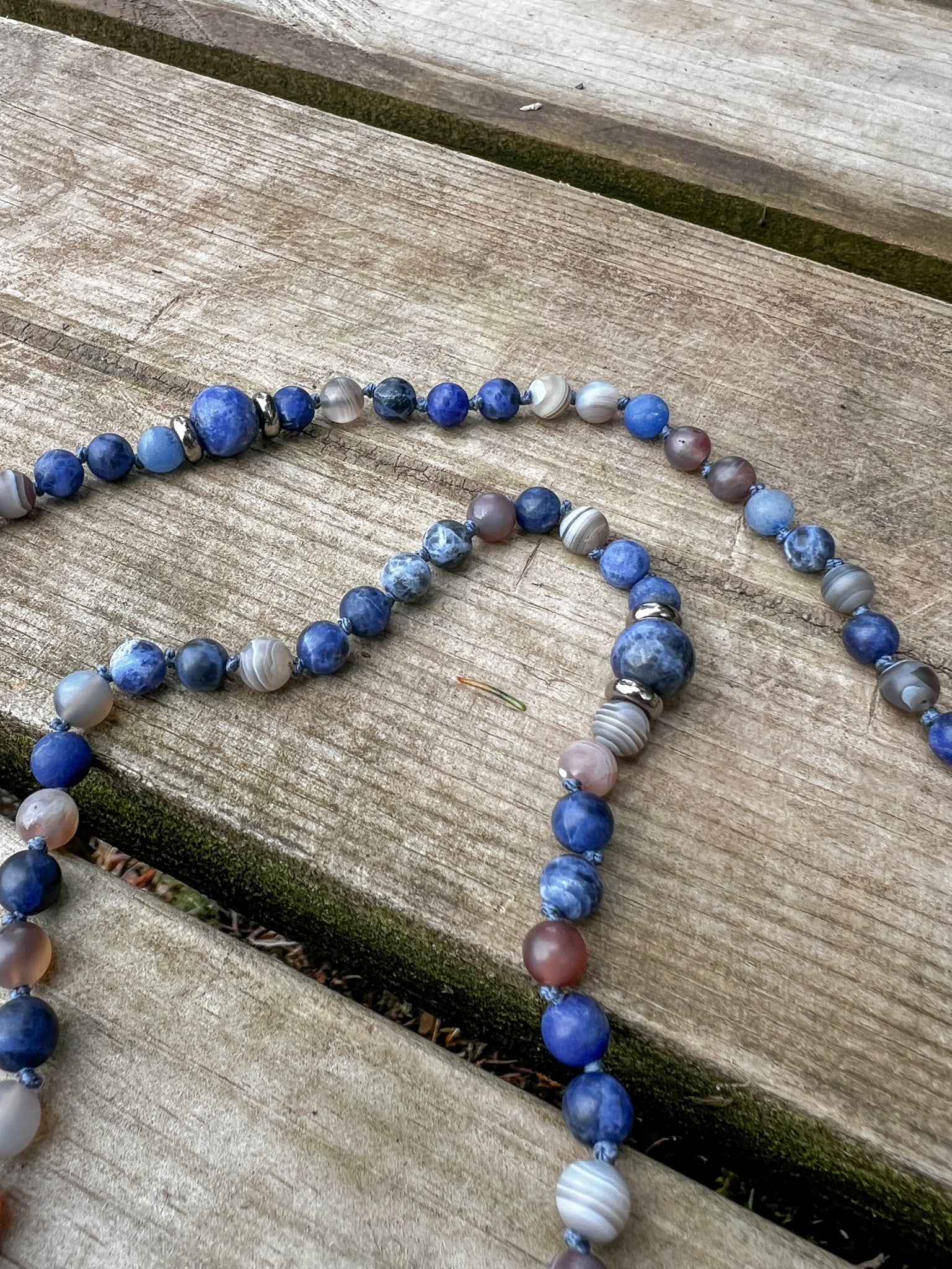 Close-up of Blue Aventurine, Sodalite, Botswana Agate, and stainless steel marker beads on the Ocean Current Mala Necklace.