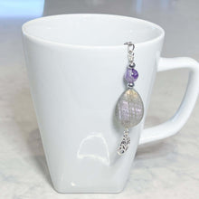 Load image into Gallery viewer, Amethyst and Labradorite Tea Strainer This tea strainer is made with a stainless steel tea ball, Chevron Amethyst, Labradorite, and Hematite beads. These stones offer clarity, transformation, and protection to the user.
