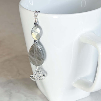Labradorite Tea Strainer This tea strainer is made with a stainless steel tea ball, Labradorite and Hematite stones with a lotus flower charm. These stones bring the user protection and encourages spiritual transformation.