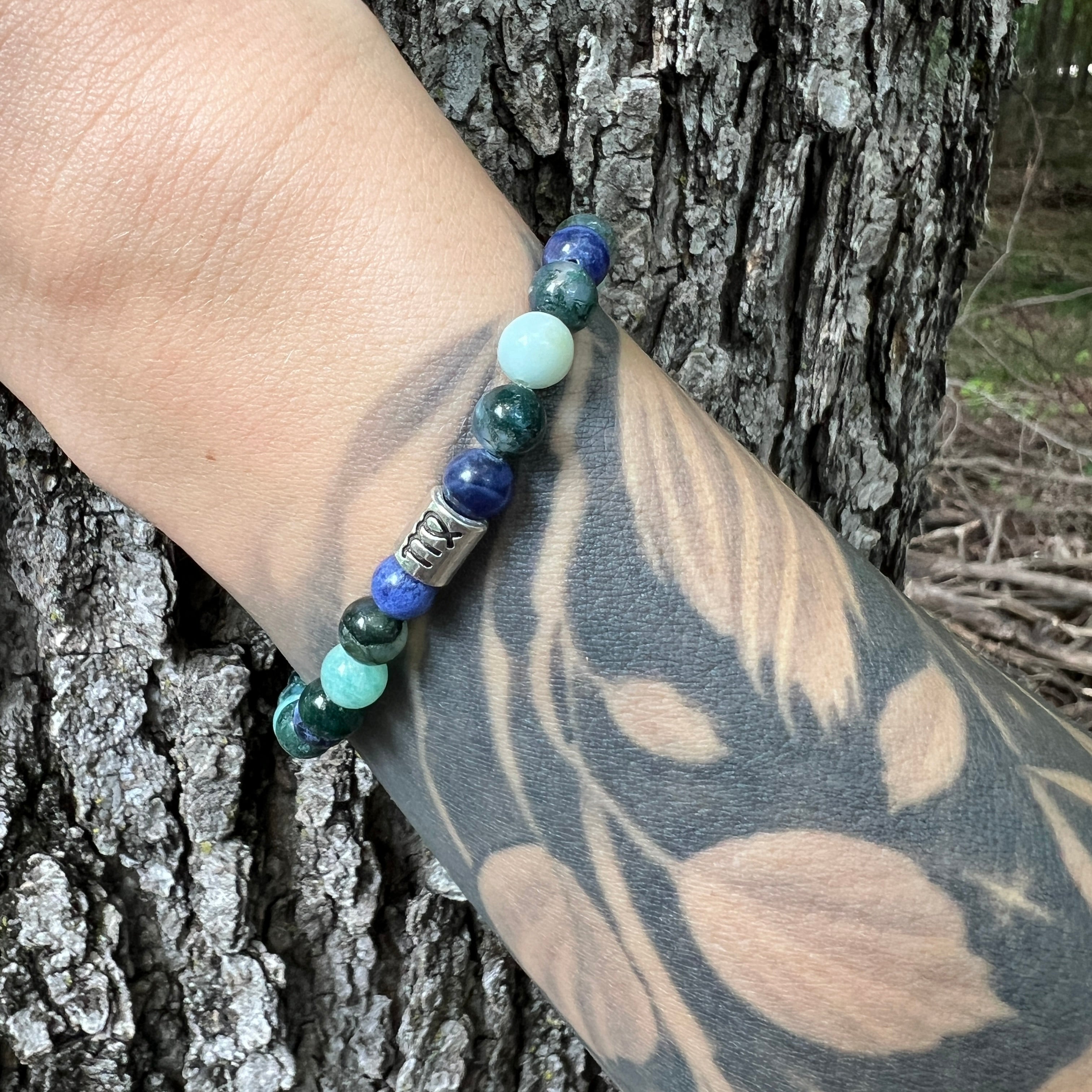 Virgo bracelet on tattooed arm with wood background.