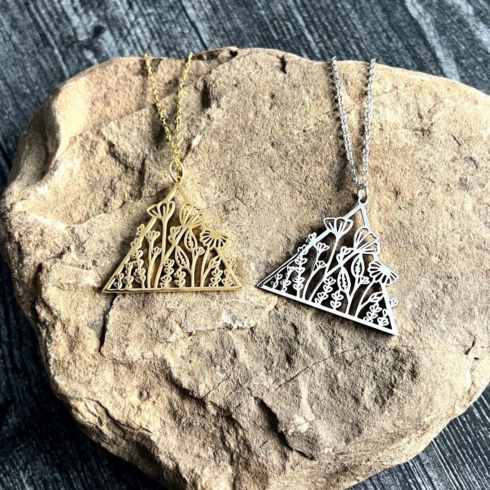 Gold and silver triangle-shaped pendants on a rock