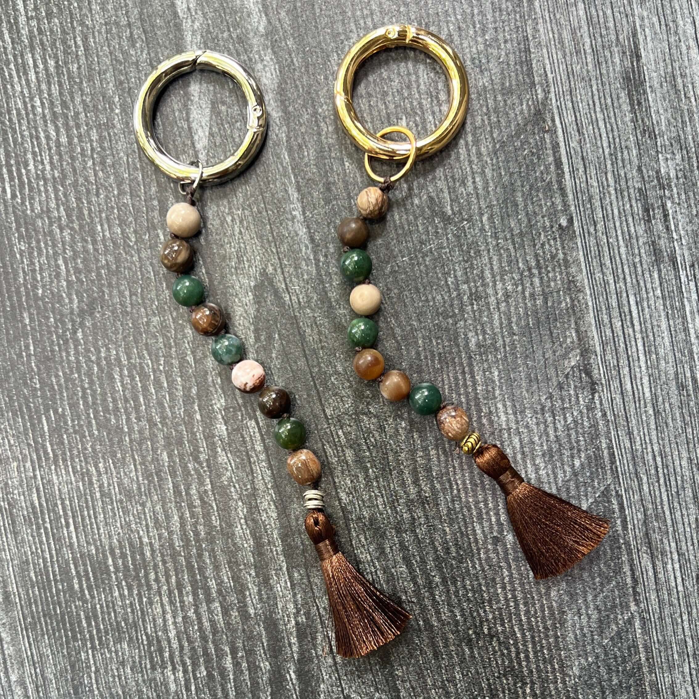 Two brown and green keychains on a wood surface.
