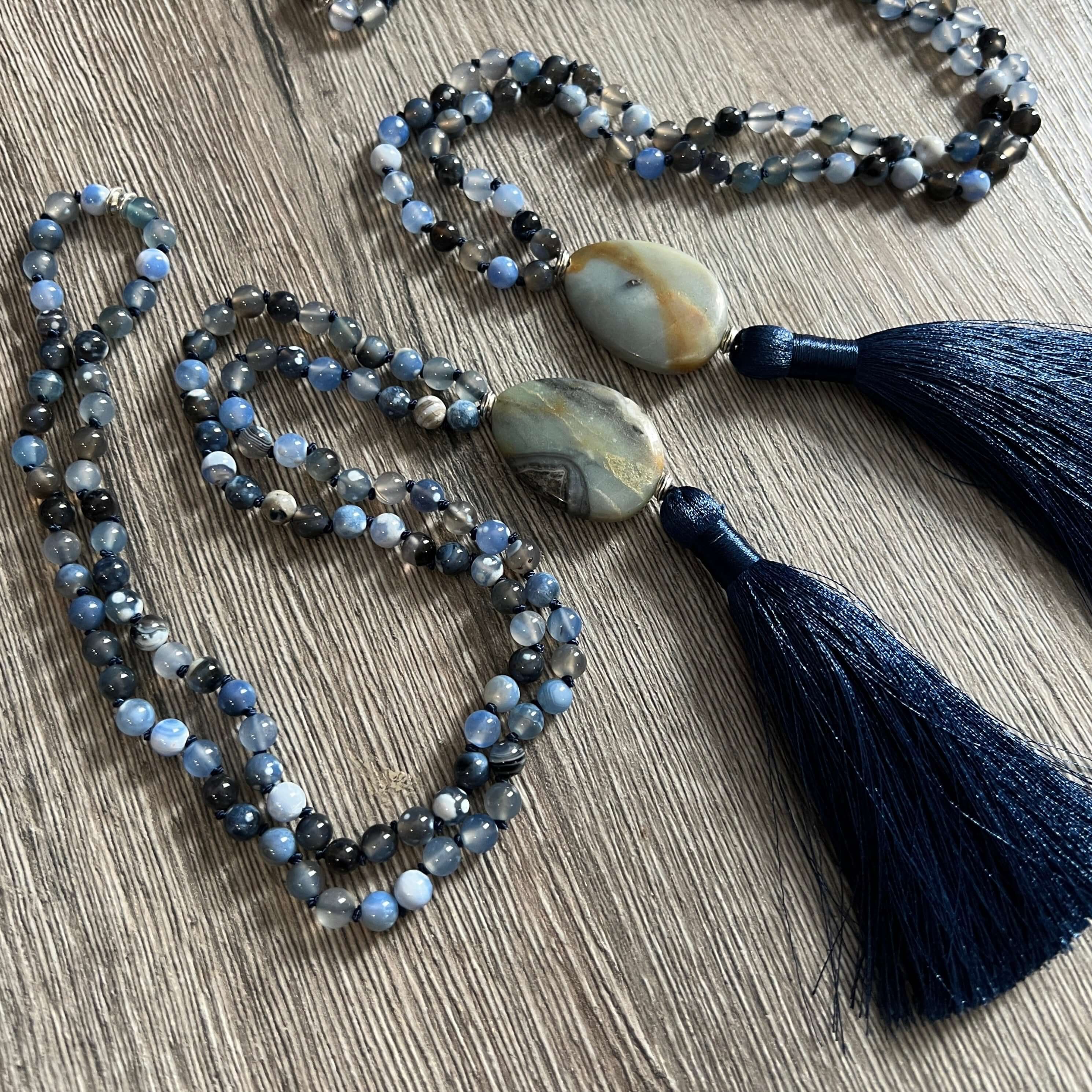 Winter Morning Mala This mala was made with Black-Blue Agate and Amazonite gemstones which provide strength and inspiration to the wearer. Zodiac Signs: Gemini & Virgo. Chakras: Third Eye, Root, Crown, Throat & Heart. Handmade with authentic crystals and