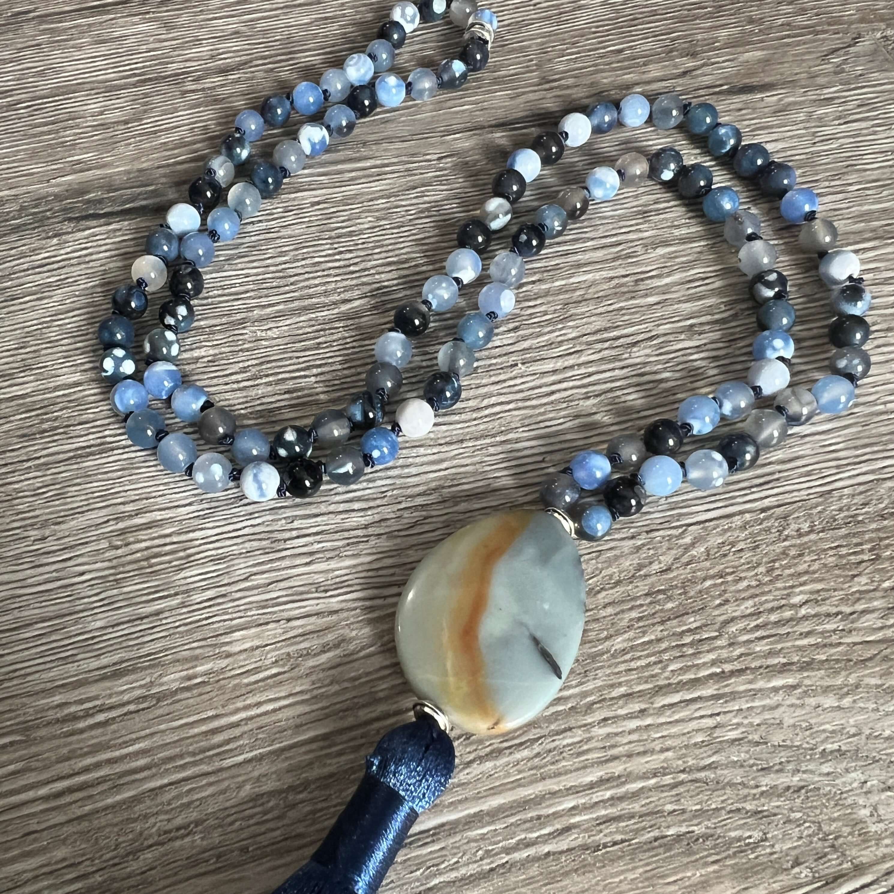 Winter Morning Mala This mala was made with Black-Blue Agate and Amazonite gemstones which provide strength and inspiration to the wearer. Zodiac Signs: Gemini & Virgo. Chakras: Third Eye, Root, Crown, Throat & Heart. Handmade with authentic crystals and